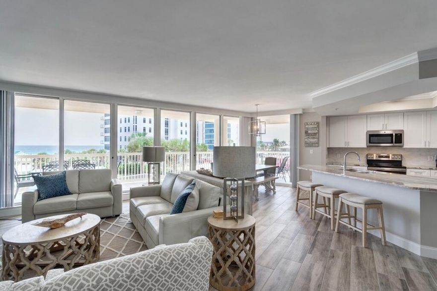 Island Paradise Retreat, from the semi-private elevator that opens directly into the foyer/living room/dining and kitchen areas. This corner wrap-around south facing unit has Destin's best sunset views at the Gulf of Mexico. Steps from Ruth's Chris Steak House, The Back Porch and The Sand Bar. Professionally decorated in comforting beachy vibes - grays and hint of Gulf colors throughout. The white marble counters in kitchen and all bathrooms and the washer/dryer area. Newer coastal wood looking tile throughout the entire condo. Entire unit is painted in a hint of gray with tan undertones. Chic leather love seat and sofa (both are sleeper/sofas). The coastal furniture is Risa's and Sugar Beach Interiors. Great residence for island living, so close you can hear the tides and watch the surf.