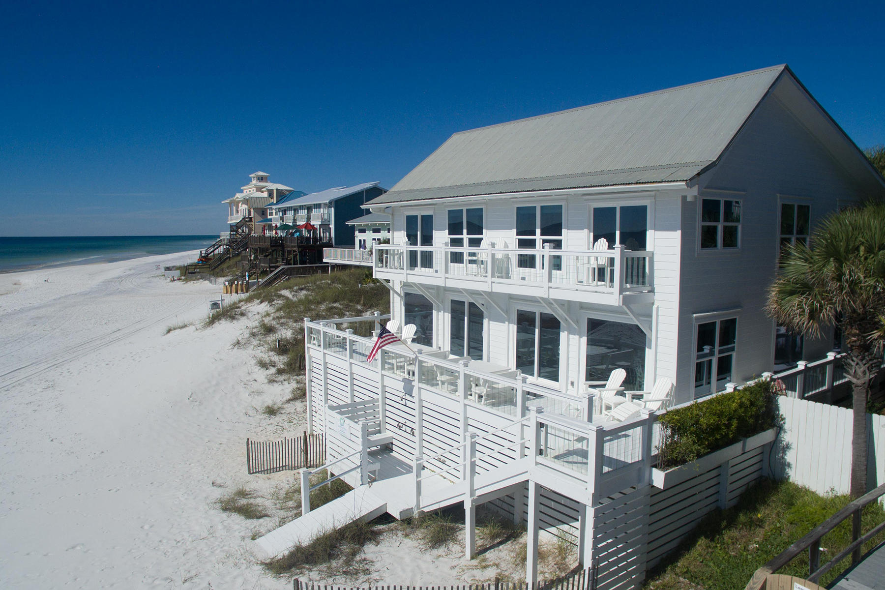 Set in a prime gulf front location, this traditional beach house encapsulates waterfront living with incredible gulf views from almost every room. Presiding on 71 feet of pristine beach frontage from its elevated position, this desirable vacation home offers a beach lifestyle that everyone can enjoy. Ideal as a second home or vacation rental, this well-appointed beach cottage has impact doors and windows, hardwood flooring and a wrap-around deck on the entire first floor. The first floor living and dining area share breathtaking gulf views with picture windows. Custom Kraftmaid cabinets, stainless steel appliances, and quartz countertops complete the gourmet kitchen. Additional wet bar conveniently provides ice and refrigerated drinks for toasting each sunset.