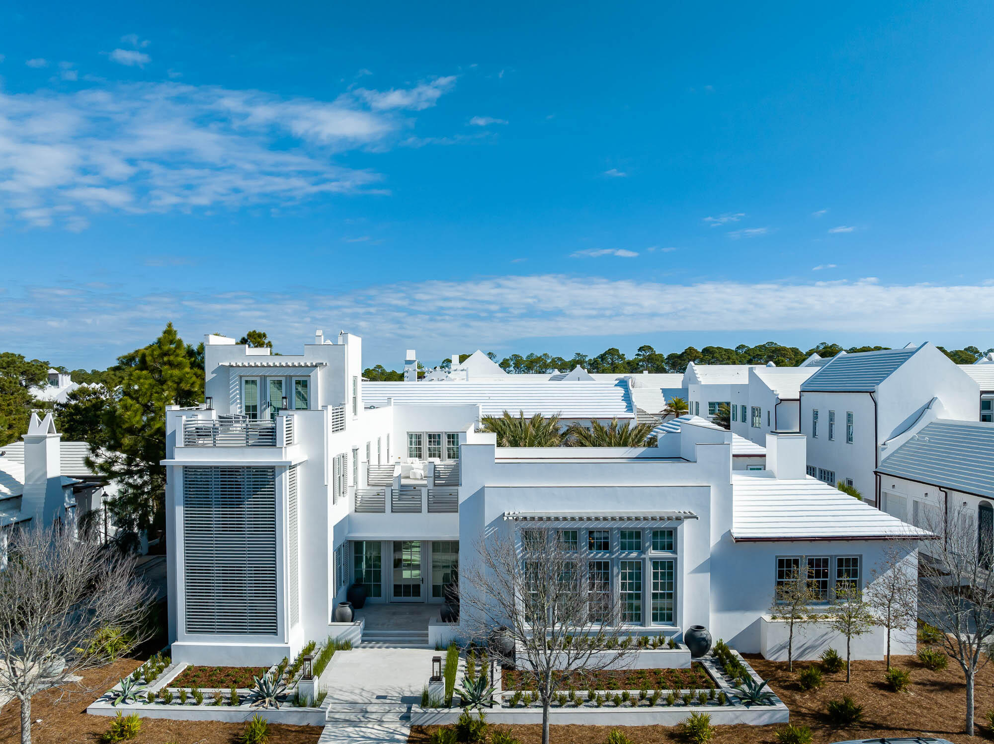 Award winning Khoury Vogt Architects does it again with this extremely rare Alys Beach Compound Home that stands alone amongst its peers. Fronting McGee Drive, the homes overlooking this street were given special distinction with generous setbacks allowing for first level terraces to give a promenade feel unique to this street alone. At 32 McGee Drive, the tone is set with an inviting outdoor entry garden that leads to a sunlit entry hall with offset pivot hinge doors that connect to an oversized Court Loggia. A large great room with concrete floors and integrally colored plastered walls looks out to a Mediterranean courtyard anchored with 4 medjool palms set amongst a sunken seating area and fire pit. A Generous courtyard pool with sunshelf and waterfall fountain is flanked by the