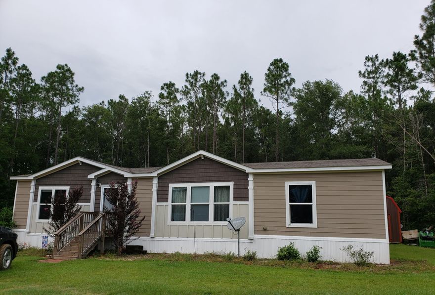 Super cute newer mobile home on 2 acres in Holt . As you enter the home you are greeted with a wood look decorative entry way that leads you in to the large living room with built in shelving . The kitchen is open to over look the living room and has a large island to gather around! The master bedroom is spacious and attached to a beautiful master bathroom with double sinks and a vanity area. You can also enjoy the deep soaker tub or the tiled walk in shower. Outside in the massive 2 acre yard is a newer shed and carport. The owner has also cleared the property line so putting up a fence could be easy. Sellers recently had the septic tank pumped and had routine maintenance on the AC.  Home will also come with washer and dryer Professional pics coming soon