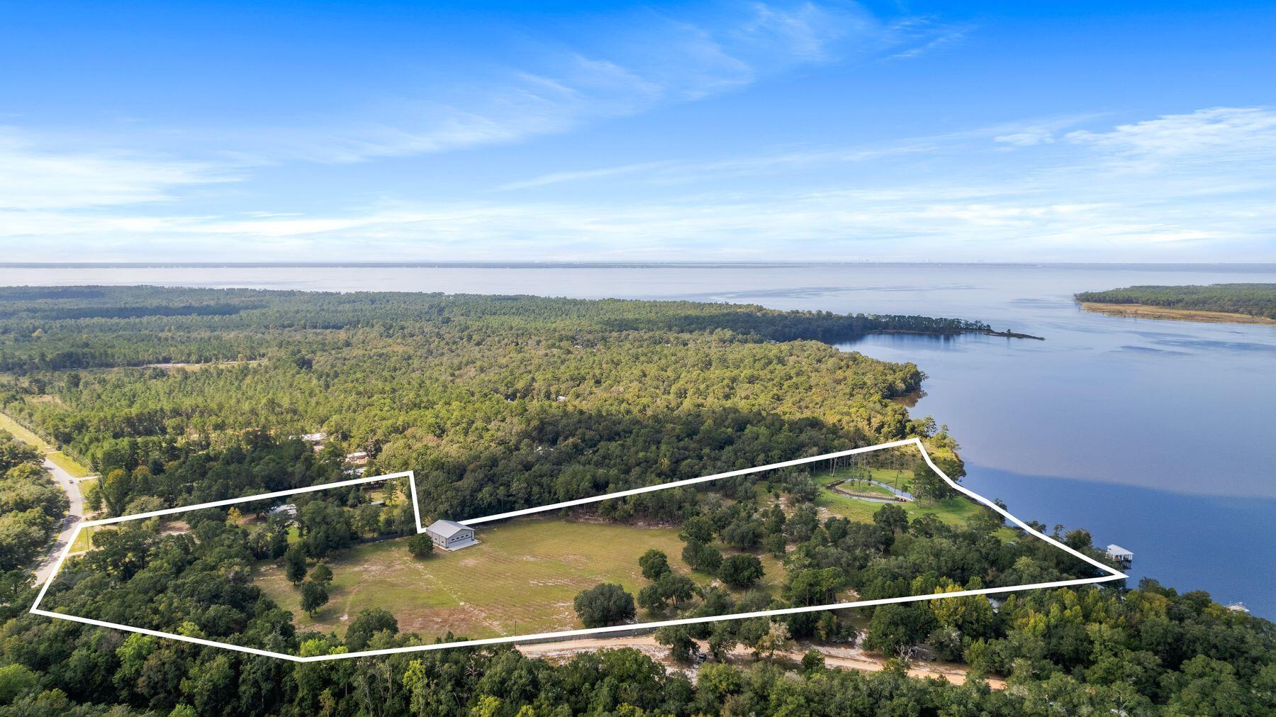 This premier development opportunity spans approximately 23.22 acres across three parcels in a private and beautiful area of Freeport! Boasting 950 linear feet of waterfront on Alaqua Bayou, this estate offers potential for a private waterfront compound or neighborhood development, complete with a private dock, boat lift, fire pit, and gated entry! With a 3,240 square foot metal building and workshop already in place, equipped with power, water, septic, and bathroom facilities, the groundwork for development is ready to go. Large canopy trees provide natural beauty and privacy, while perimeter fencing enhances security. Access to the property is conveniently located off County Highway 83A and Dexton King Road. Utilities, including city water, power, cable, and sewer, are... available along County Highway 83A. This opportunity also has an FAA approved helicopter land pad on the property that is also approved by Eglin AFB as it lies under their restricted airspace. Additionally, the southernmost parcel features an existing residential structure, and there's significant potential for future single-family home development with a Conceptual Master Plan in place (subject to permits and changes). A private helipad has been approved by the State (pending final activation), adds a luxurious touch to this property. This prime location offers an incredible chance to create a one-of-a-kind residential development or private estate, the choice is yours.   A Conceptual Master Plan is in the photos and is shown only to represent design intent. Layout, density and lot sizes are subject to change to reflect local and state regulations and approvals. Call today for more information or your private viewing.
