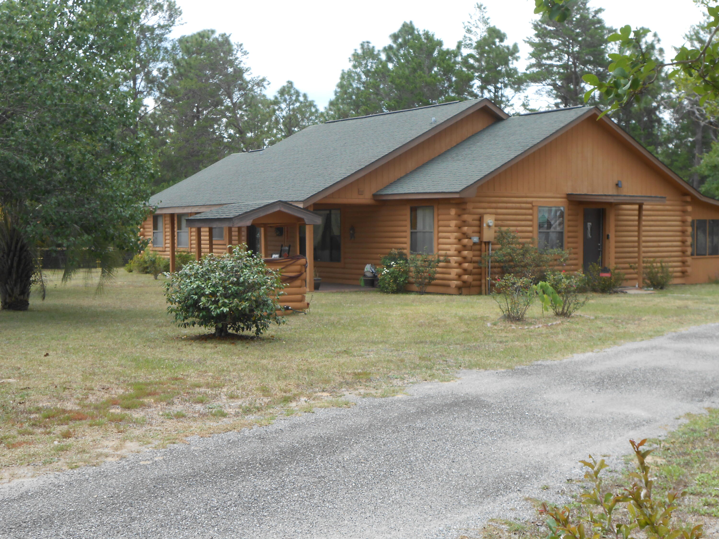 This is a BEAUTIFUL Log Cabin on 1.39 acres. It is about half way between Crestview and DeFuniak Springs, FL. A Covered Front Porch designed for a rocking chair (s). 12 foot ceilings in a living room and dining room combination. Ceramic tile flooring in the main areas and baths. Kitchen has Birch cabinets and breakfast nook area, but the refrigerator will not convey in the sell. There is a screened-in back porch with a fenced area for a pet to exercise. The detached garage has a 1/2 bath and separate storage area. Yard is landscaped beautifully with many bushes and trees. Also yard supports a well for irrigation of the yard.