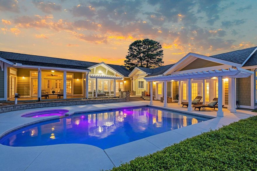 Situated on a mature half-acre lot on a quiet cul de sac, this elegant home boasts majestic lake and golf views. Enjoy an elevated and serene setting that captures this Florida cottage style with coastal design and color palette.  Follow the brick pavered driveway to an oversized three car garage and a flagstone pathway leading to the impressive covered entrance. Inside, this beautiful home exceeds expectations with gleaming hardwood floors, energy-efficient windows, custom drapes and a wall of custom bookcases for displaying family photos and treasures. Bathed in natural light, the open floor plan is ideal for entertaining. There is a wet bar and a generous chef's kitchen with a large granite-topped breakfast bar ideal for laying  hors d'oeuvres before dining.