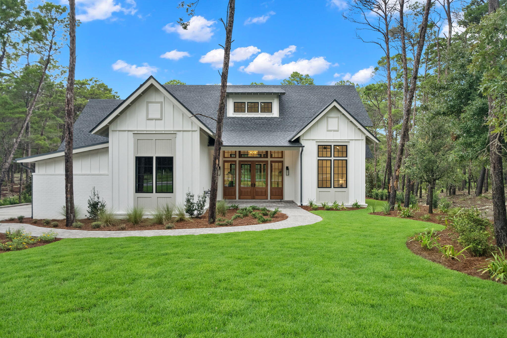 This stunning NEW CONSTRUCTION home Wild Heron is a single level home where modern craftsman design meets resort-style living. Welcome to a home where timeless design and modern luxury meet coastal serenity--just minutes from 30A and nestled within the gates of Wild Heron, one of Panama City Beach's most desired, fast growing communities on the shores of Lake Powell. Thoughtfully designed and construction just completed, this highly desirable, single-level masterpiece spans 3,300 square feet under roof and offers 2,401 square feet of interior living and over situated on a generous .37-acre homesite that backs up to conservation area offering both privacy and peaceful views. From the moment you step through the 8' solid Mahogany French doors, you're greeted by a sense of understated luxury. As you enter, you're greeted by a showstopping 24' cathedral vaulted ceiling in the living room, 12' ceilings flowing throughout, and an open concept anchored by a natural gas fireplace. Arched doorways add architectural charm and warmth, while modern, black Andersen windows and French doors to the patio flood the space with natural light. Step outside the living area to your private oasis where you'll find your own private, saltwater pool surrounded by a pavered deck, lush landscaping, and a vaulted, covered back porch plumbed for an outdoor kitchen.
The open-concept layout is both inviting and functional, perfect for effortless entertaining and everyday living. Enjoy white oak flooring throughout, along with a curated palette of classic tile selections in the bathrooms, mudroom, and a timeless black-and-white checkered tile mud room and butlers pantry.
The kitchen is timeless and classic featuring white shaker custom cabinetry on the perimeter with a warm white oak wood island, Quartz countertops, and a full suite of Bosch appliances, seamlessly blending style and utility. A spacious butler's pantry off the mudroom and kitchen adds even more prep space with built-in shelving, generous counters, and a beverage fridge.
The primary suite is a true retreat with stunning conservation area views, shiplap clad vaulted ceilings, a spa-like primary bath with a soaking tub, zero-entry tiled shower, and a custom walk-in closet with double vanities paired with modern tile selections. With four bedrooms and three baths, this home offers a split floor plan that prioritizes privacy and comfort. All bedrooms offer walk-in closets, three bedrooms of the four bedrooms feature vaulted ceilings and a generous size Jack n' Jill bath with separate vanity areas allow for the best use of the third bathroom.
The 2-car garage offers tall ceilings for expanded storage and an EV-car charger for convenience of those with electric vehicles or golf carts. Crafted with enduring materials, brick and Hardie siding, this home captures the charm of classic craftsman style with the function and efficiency of modern construction with a coastal elegant twist.
Spanning 734 pristine acres along the shores of Lake Powell, Florida's largest coastal dune lake, this extraordinary community invites residents to slow down, breathe deeply, and savor the beauty that surrounds them. Morning strolls along miles of tree-lined walking trails, afternoons spent lounging at the resort-style lakefront pool, and evenings by the boathouse pavilion watching the sun set over the water, this is the rhythm of life here. With access to a community dock, fitness center, playground, and the opportunity to lease private boat slips with power lifts, Wild Heron was built for those who crave both adventure and serenity.
For those seeking the ultimate in exclusivity, Watersound Club membership elevates the experience with multiple private Club opportunities. In Wild Heron, enjoy the challenge of Shark's Tooth Golf Club, a Greg Norman-designed 18-hole masterpiece. Unwind at the clubhouse, sharpen your swing at the driving range, or hit the courts for a game of tennis.