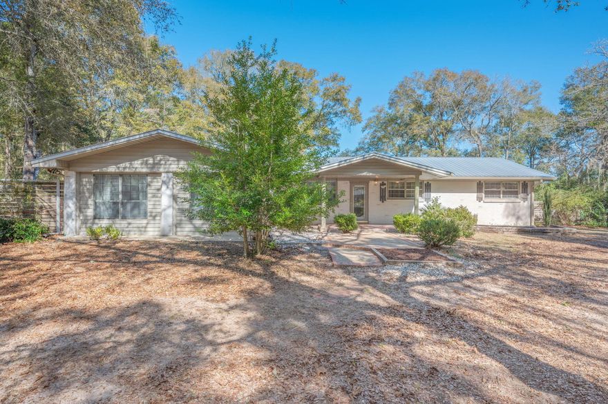 Tucked away on beautiful acreage, this property blends privacy, thoughtful updates, and room to roam with a picture perfect water view, all less than five miles from historic DeFuniak Springs. A charming brick walkway leads you to a welcoming covered front porch and into a bright foyer that opens into the heart of the home. The kitchen is a standout, featuring custom wood cabinetry, butcher block countertops, a spacious island, and stainless steel appliances, perfect for everyday living and entertaining. The oversized living room offers incredible flexibility with an additional space ideal for a home office, playroom, or creative studio. Character shines through with details like German schmear brickwork and stylish shiplap accents throughout. Enjoy peace of mind with a durable metal roof installed in 2020 and relax on the covered back porch while taking in serene views of a neighboring pond. A beautifully finished full bath features tiled shower walls with a timeless herringbone design. Outside, the property truly delivers. A 36x30 pole barn includes 720 sq ft enclosed, offering endless possibilities for a workshop, studio, or additional storage. A detached brick two car carport and garage complete this exceptional property, making it a rare find that offers space, style, and scenery in one incredible setting. (Roof 2020, HVAC 2018, Hot water heater 2021)