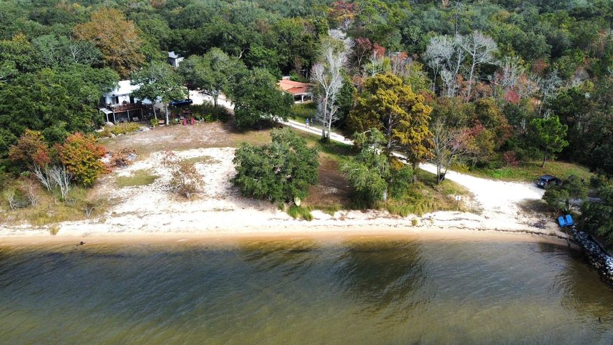 Nestled in the oaks, down a gravel road you will find this Old Florida beach house. As close to waterfront as you can be without actually being waterfront. Just a short stroll to the waters edge and you can be paddling, fishing or swimming. The property has a detached garage with huge double doors and side area for more covered space. There is a separate guest suite off from the back porch with a full bathroom as well. The main house and guest suite is constructed from cement block, so insulation is incredible. The main house has a NEW metal roof and HVAC with warranty. And the entire property is well maintained. So many places to just sit back and relax, from the carport to the back yard covered patio and down to the waters edge. Only 5 miles from Hammock Bay and 9 to the Mid bay Bridge.
