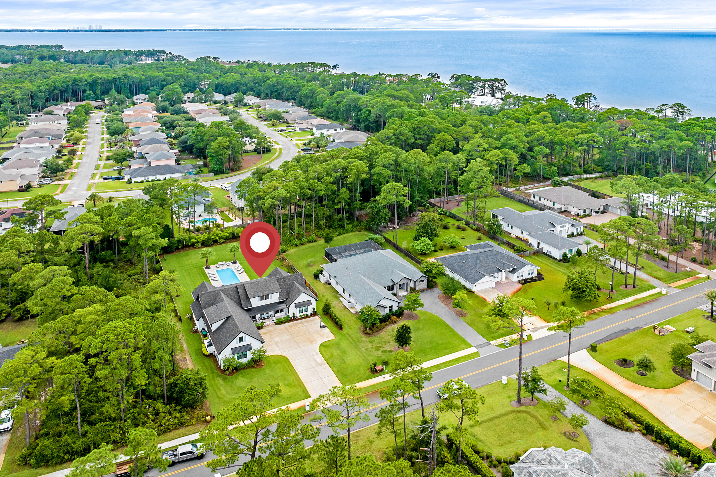 Coastal elegance meets everyday comfort in this stunning 5-bedroom, 4.5-bath custom home by Cogent Building Group and Bird Dog Design Co. Thoughtfully curated for a growing family, this home also features a private office, separate media/living room, and expansive 3-car garage. Enjoy bay views from the front porch and relax in the 40' gunite pool with sun ledge and pool heater, situated on over 1/2 an acre. Interior highlights include 10' ceilings, vaulted living and primary bedrooms with white oak beams, engineered hardwood flooring, designer lighting, and custom window treatments. The chef's kitchen is equipped with quartzite countertops, Thermador gas cooktop, soft-close wood cabinetry, and a filtered drinking water system. Bathrooms feature marble countertops and designer tile throughout. Built for both beauty and performance, the home offers foam insulation in ceilings and between walls, 2x6 exterior construction, vinyl impact-rated windows and doors, solid core interior doors, and insulated garage doors. Additional features include two gas fireplaces, Calacatta marble fireplace surround, reclaimed brick on the front and back porches, copper gutters, custom built-out closets, and a Sonos sound system with ceiling speakers in both living areas and on the porch. Smart and secure, the property also includes a full alarm system, three exterior cameras, a safe room/gun room in the garage, and an electric car charger. Whole-home water filtration and air purification systems provide added peace of mind for health and wellness. Located in a desirable neighborhood with walking paths, ponds, pickleball, tennis, basketball, restrooms, parks, and more.