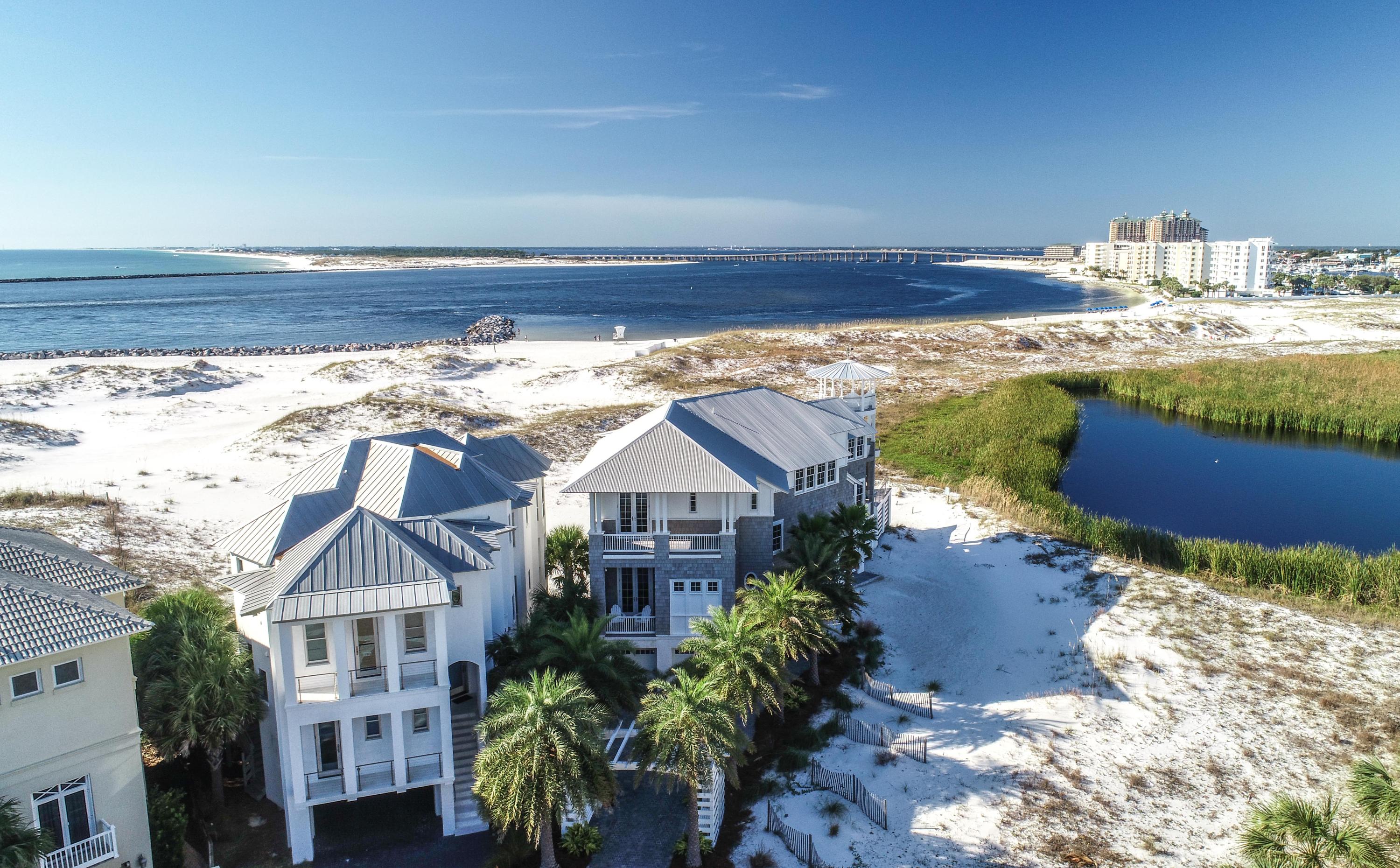 This Gulf front and Lake front, Savoie design, fully furnished, custom home with Professional Interior Design by Beau Interiors, is the most unique home on the entire Emerald Coast. Situated in a Gated Community, on 'The Point' and facing west/southwest, every room in the house faces the Gulf, with deck access, to take advantage of spectacular Gulf sunsets 365 days per year. On the shores of a Coastal Dune Lake, enjoy migratory birds and wildlife year-round. Watch the Destin Fishing Fleet heading to sea and returning home with a sunset backdrop. Completed in 2018 and built above and beyond Dade County codes, with steel beam construction, this Coastal Chic home is built for outdoor living, offering almost 2,000 sq. ft. of deck space, (1,300 sq. ft under roof), an Infinity pool with fire