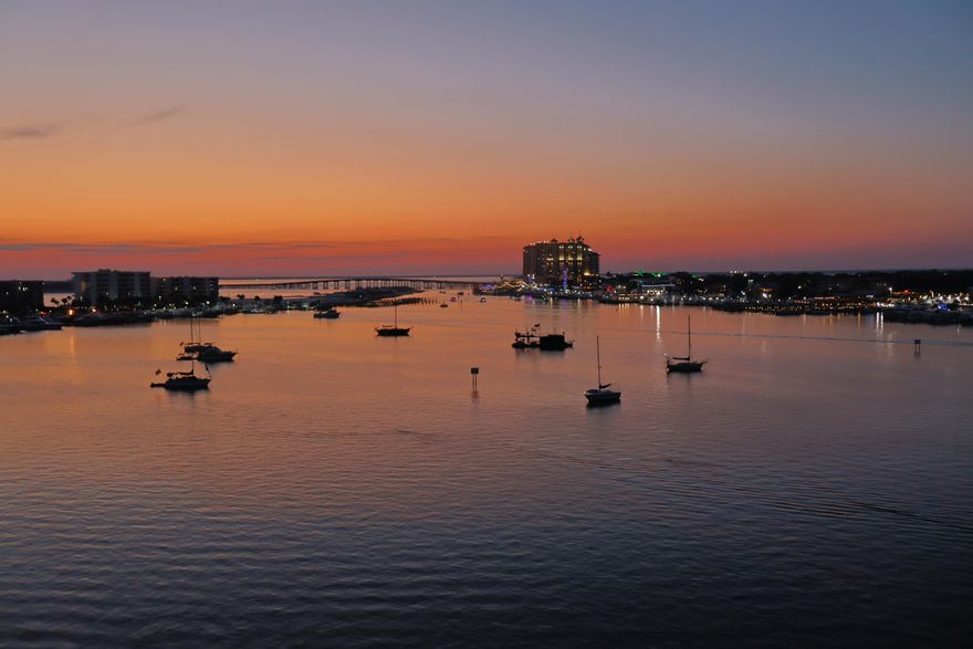 Your breathtaking waterfront story begins here, from sunrise to sunset. Perched on the top floor of a gated harborfront community, this two-bedroom, two-bath penthouse offers a front-row seat to Destin's most captivating scenery. From seasonal fireworks sparkling across the sky to the constant rhythm of passing boats, every moment feels like a postcard. For the boater, this residence is unparalleled. A private boat slip with a 16,000-pound lift -- including a walkboard -- accommodates vessels similar in size to the 31-ft. Regulator currently on site, which is also available for purchase. Rare among waterfront condos, the property features two of only six garage parking spaces located under the building, as well as a private storage unit. Two expansive balconies frame sweeping 180-degree views of the harbor, East Pass, and the gulf, offering the perfect setting for dining, grilling, or simply soaking in the sunsets. Inside, an airy open-concept layout showcases a modern kitchen with sleek white cabinetry and newer stainless steel appliances. The living room is anchored by a built-in wet bar, ideal for entertaining, while large sliding glass doors in both bedrooms and the living area open to the water, ensuring the views never fade from sight. The community itself offers a harborfront pool, boardwalk, and gated boat dock with 28 slips. Two deeded beach access points on Holiday Isle are also included. With a minimum rental term of 12 months, the community preserves its serene, residential atmosphere while offering easy proximity to beaches, dining, shopping, and the Destin Executive Airport. Blending exclusivity with unforgettable water views, this penthouse retreat offers a lifestyle as rare as the sunsets it frames.