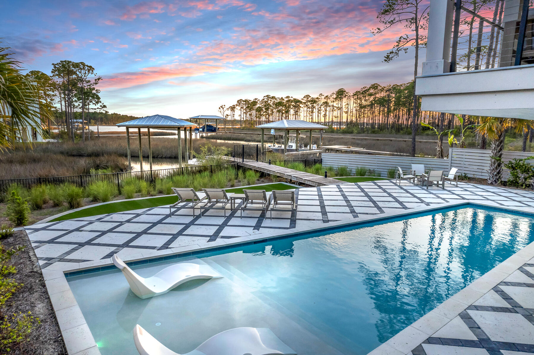 Take a slow drive down this quiet street just minutes from 30A's bustle and beaches but worlds away. Perfectly positioned along the water's edge and sitting high above a captivating bayou, you'll find this architecturally significant, modern coastal masterpiece. Every element is visionary yet functional, including fabulous furnishings (most remain).Built in 2022 and improved by the current owner, this home is timeless in detail and rich in amenities. Over 1/2 acre of outdoor space includes a full-sized pool with tanning ledge, highlighted by grass-lined pavers, and surrounded by native landscaping with a clever AstroTurf lined play yard.