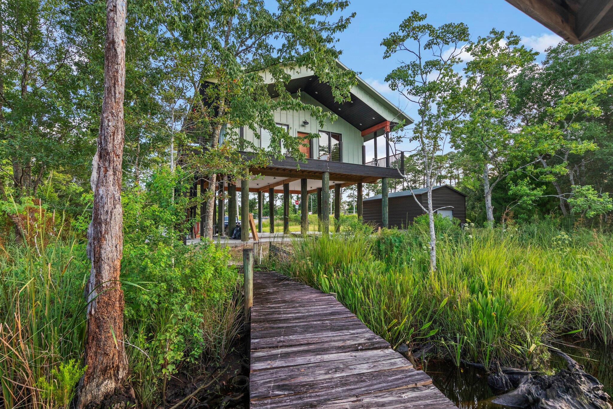 Brand new custom built river front home by Navarre's best custom builder! 8536 Kingsley Place, on East River in the beautiful beach town of Navarre, Florida! Large lot: 161' waterfront x 107' deep, paved road. Built to Florida's stringent Hurricane Building Code and FEMA standards. Not only will you live on your own river front paradise with access to the bay and Gulf, but you're only 5 minutes from some of the world's most fabulous white sugar sand beaches on the Gulf of Mexico! Bring your boats; skis; jet skis; pontoons; inner tubes; family and friends and get ready for practically year 'round Florida fun on the water! And how would you like to have a home office with a waterfront view!!! Excellent location and convenient to everything you need. PIER FROM HOUSE TO WATER; COVERED DOCK; fish from your own yard, or launch your boat from your own covered dock and float to the Bay or the Gulf; outdoor shower; large 16' x 20' storage shed; sodded lawn. Well built custom home by the area's best custom builder! Hands on craftsmanship! Waterfront home on pilings with wrap around porches with composite decking materials; clear view stainless steel cable deck railing for unobstructed views; Metal roof; State of the art sewage system; Rinnai hot water system. Large kitchen with lots of cabinets; large pantry; custom designed and built kitchen island with butcher block top and lots of storage; stone countertops; stone backsplash; custom built light fixture over sink; All stainless steel appliances included - 26 cubic foot refrigerator; gas range; dishwasher; garbage disposal; vented microwave; inside laundry area includes washer and dryer. Exterior is hardie plank siding in board and batten design; 2 x 6 exterior wall construction; spray foam insulation in walls, ceilings and floors; cathedral ceilings in main living area with tongue and groove real hardwood; tongue and groove real hardwood on porch ceilings; real hardwood floors throughout; tile in wet areas; custom built solid wood trim throughout and around windows and doors; matte black hardware; solid wood interior doors; solid mahogany exterior door. Concrete grid driveway under pilings and lots of storage and parking under pilings; paved driveway with lots of additional parking. Easy access to and from property and to and from the interstate and the beaches. Clear view Low-E vinyl windows for lots of natural light with unobstructed views; windows tilt for cleaning; numerous can lights throughout. High ceilings throughout. Huge walk in tile and marble shower with built in soap dishes and glass shower door; custom built bathroom vanity with stone countertop. Hurricane protection Fabric Shield for doors and windows. Open living plan - 2 bedroom, 1 bathroom, large rooms: Approximately 780 s.f. living area, but LIVES LARGE with plenty of room for bunk beds, day beds, trundle beds, etc.. Home conveys with ceiling fans; furnishings to sleep 6, but can sleep 9 easily; also conveys with dining table and stools for 4, 4 end tables with extra shelves and USB ports, 4 bar stools at kitchen island, wall mounted t.v., area rug, 1 triple bunkbed, 3 chairs that convert to recliners and beds. This is your perfect waterfront home for years of making wonderful memories and enjoying all Florida has to offer, or as an investment vacation home or rental in one of Florida's most beautiful beach towns