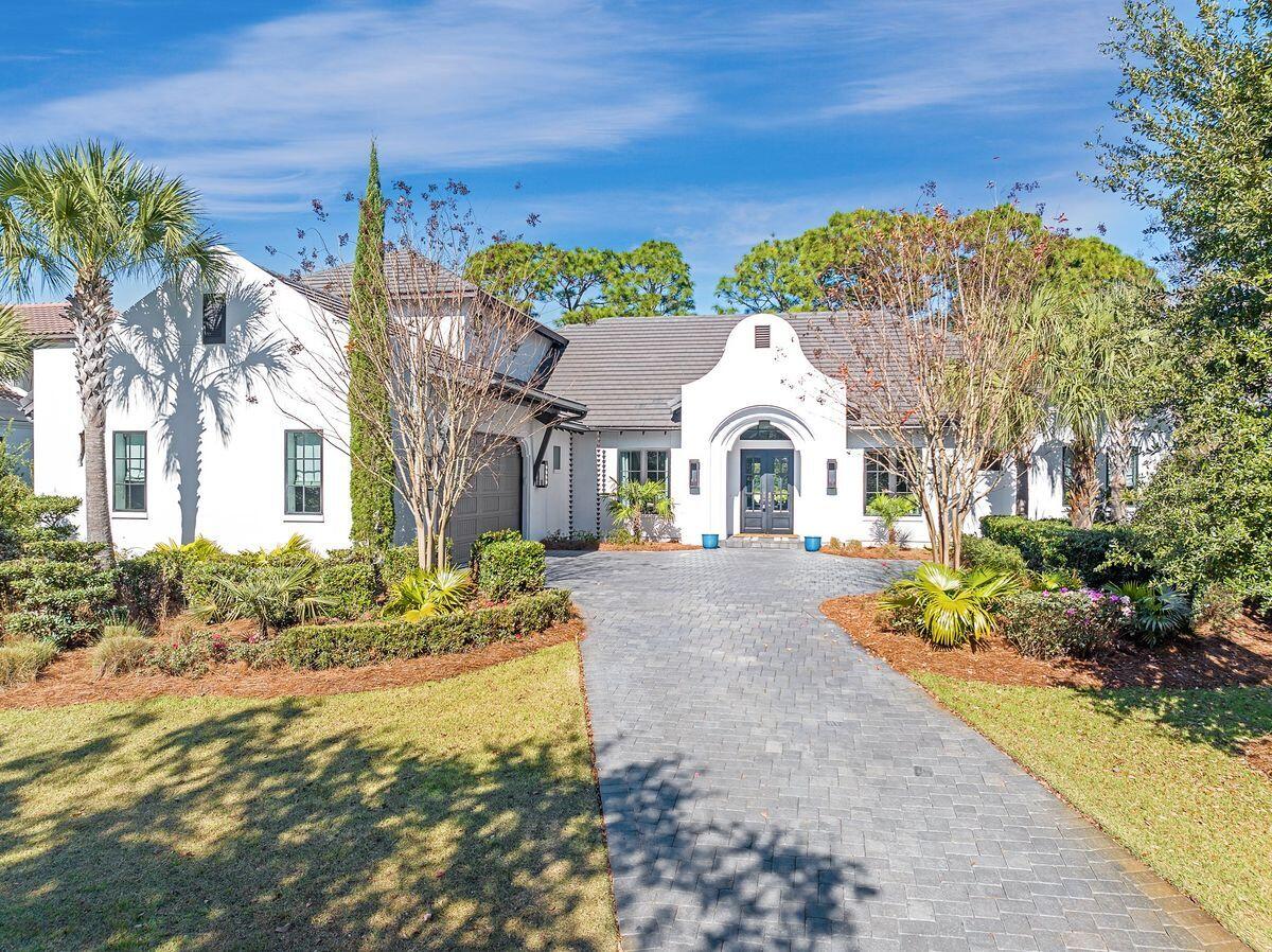 This stunning Burnt Pine home is nearly new construction within an established community. Golfers will be in paradise with views of the 12th green and lake and access to four outstanding golf courses in the wider Sandestin community. Approached from a quiet, leafy street, this magnificent five-bedroom home has a brick-paved driveway cutting through the mature landscaping to a two-car garage. Beneath the slate roof, the stucco exterior is enhanced with decorative, yet practical, rain chains. Sheltering within a prominent covered porch, the steel front door opens into a foyer, leading into a huge great room with views of the pool and golf course glimpses beyond. On either side of the foyer, there's a spacious home office and a formal dining area for entertaining. Twelve-foot and vaulted ceilings create a great sense of space in the home. Fully appointed, the chef's kitchen has stainless appliances brandishing high end brands, including a 48-in. Wolf range, Bosch dishwasher, and a Sub-Zero refrigerator. A pantry with a wine cooler and a separate laundry are tucked neatly out of sight. Quartz countertops grace two oversized islands; one for food prep and the other for casual dining and pre-dinner cocktails. The adjoining living space has soaring vaulted ceilings and a gas supplied brick fireplace. Wall accents and built-ins are all part of the upscale designer lighting and interior decor. Wood laminate flooring flows towards a bank of windows and doors leading to a courtyard with a private pool. Gushing water spouts add visual and aural effects. A built-in summer kitchen makes outdoor entertaining easy. Beyond the gate, an open grassy backyard offers green space for relaxing while mature podocarpus trees provide ample screening from the neighboring homes and a beautiful view corridor to the 12th green and lake. The split floor plan of the home puts the primary suite in a separate wing on one side of the house with three guest bedrooms and three bathrooms on the opposite side. The master suite is lavishly appointed with a stacked natural stone wall and custom wallpaper. Two custom closets have built-ins, while the opulent bathroom includes a freestanding tub, a tiled shower with dual shower heads and a twin vanity, all arranged beneath a glittering chandelier. Wood-tread stairs wind up to the second floor, a versatile space currently used as an additional bedroom. It boasts a walk-in closet, a generous sitting area and a private bathroom with shower. Sandestin is known for its outstanding amenities, including four golf courses, 15 tennis courts, and a state-of-the-art fitness center within the 2,400-acre complex. Head to the marina at Baytowne Wharf for boating, watersports and waterfront dining, or browse the boutiques and specialty shops within Baytown and Grand Boulevard. For a day at the nearby beach, take your golf cart through the tunnel under Hwy 98, or take a complimentary tram making the experience easy and hassle-free.