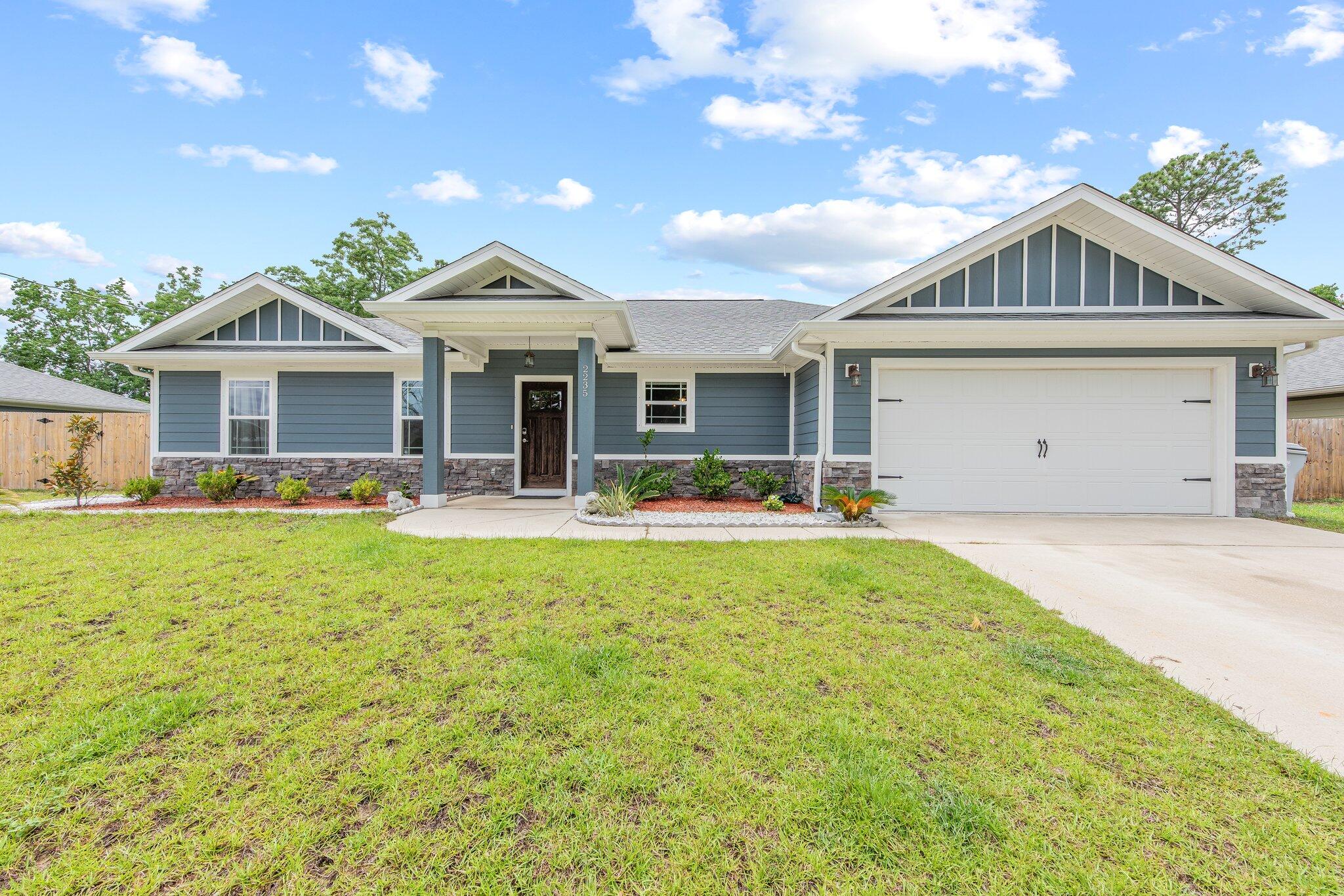 Make your plans to see this beautiful 2018 home in East Navarre. Just minutes to Navarre Beach, groceries, dining, Hurlburt AFB and more. This lovely home has a beautiful look with its stone veneer and Hardie cement siding and covered front porch. It's a spacious 1867 ft with 4 bedrooms and 2 bathrooms. An open floor plan and split plan with the Master bedroom on one side of the home and the other bedrooms on the other side. This home has some wonderful custom features such as the 9'and 10' double tray ceiling in the living room and single tray ceiling in the master bedroom. The open living area boasts custom built-in shelving, custom paint throughout, gorgeous wood-look laminate plank flooring throughout much of the home and tile in the wet areas. Pendants lights over the kitchen bar an