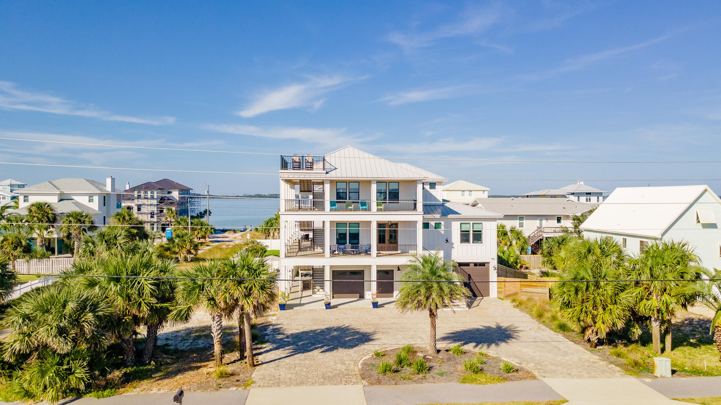 Rare opportunity, New custom built luxury designer, 6-bedroom, 5.5-bathroom house features a high level of sophistication. Built in 2018, and a new addition under construction, this home features direct gulf and sound views boasting over 2500sqft of exterior decks, and a 4th story sky deck overlooking 360 degrees of the island. On the main level, you walk into a large open concept living/kitchen area boasting a large eat-in kitchen featuring a 6x4 island, 6-burner gas stove, double dishwashers, quartz countertops, wet bar, etc. Off the living room is the washroom and two king master suites with en suite bathrooms each with fully tiled and glass showers, quartz countertops, and walk in closets. Included in the master is a cubby room featuring two built in bunks that can double as an office/study. Up the stairs to the 3rd floor is an additional 4 bedrooms and 3 full bathrooms. Past the elevator is the 1st bedroom featuring a 6-person built in bunk room with double Tv's and game station setup. 2nd bedroom is a large king bedroom with views of bay. These two bedrooms share the joined bathroom at the end of the hallway with a separate toilet room and coffee/wine bar. The 3rd bedroom is a queen bedroom with an en suite bathroom featuring a fully glassed shower and custom cabinetry in the bedroom. The new addition adds an additional 300+sqft that will add one more bedroom, bonus room, and a shared bath. The bonus room will features a double custom built in bunk with a jack and jill style bathroom that is shared with the 4th bedroom that has direct views of the sound. Off the kitchen is the large screen enclosed porch with a built-in gas fireplace, TV, and lots of entertaining space. The exterior of the house includes finished porch ceilings, trex decking, a large 3 car garage, hot tub, and an exterior kitchen with quartz countertops. The new 12x28 gunite pool includes a 400,000BTU heater and fully fenced in yard. Property comes fully furnished with great rental history!