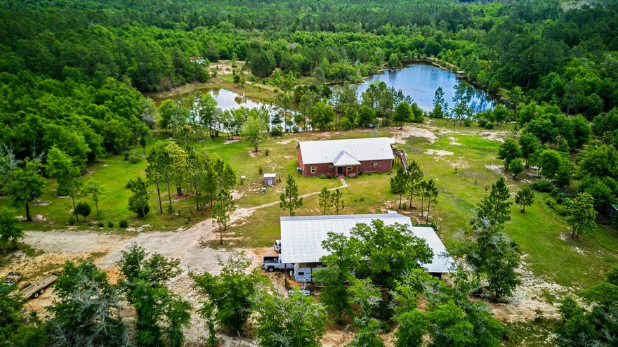 Incredible 40+ acre homestead and wildlife paradise-where comfort, self-sufficiency, and nature live in harmony. This all-brick custom home offers over 4,000 sq ft of quality craftsmanship, construction and thoughtful design. The open, split-bedroom layout includes a spacious primary suite with tiled walk-in closet. The kitchen features solid wood, soft close cabinets, stainless appliances, smooth-top stove, and a walk-in pantry/safe room. There's a natural wood breakfast bar, a dining area, 9' ceilings and crown molding, full guest bathroom, recessed lighting and wood look, ceramic tiled floor throughout. Plus, bull nosed corners, and impact resistant/wind rated windows. Upstairs includes 2 additional bedrooms, full bath, and room for an office or gaming space. One bedroom opens to a private porch, offering tranquil views of the windmill and surrounding landscape. There is extensive storage throughout, plus downstairs covered porch overlooking the ponds. A massive 80x40, pole barn provides workshop space, and generous covered parking for vehicles, RV and equipment. Above is a 960 sq. ft 1bdr/1 bath apartment, (included in the total sq. footage) featuring high ceilings, LVP flooring, a fully equipped kitchen, shaker style cabinets and subway tiled backsplash. Perfect for guests, Rental, or extended family.
2 stocked ponds, (1 is  2.8 acres, spring-fed & aerated by the windmill) are teeming with bass, bream & shell cracker. A motorized floating dock adds charm, function and fun. There are 2 wells on site. The rock well is 525-ft deep and taps into the limestone aquifer, delivering some of the purest water available. 
Just some of the additional features include a chicken coop w/chickens, 100's of blueberry and blackberry bushes, grapes, persimmon, a separate shed with metal roof that could be turned into more living space, and even a clover field to attract the plentiful deer and wildlife here. This one of a kind property is gated and private. Just 45 minutes from the white sandy beaches of Navarre, an hour from Destin, and convenient to everything Pensacola has to offer. This is a RARE opportunity to be able to live, hunt, fish and thrive off your own beautiful land! Shown by appointment only. As always, buyers should verify all information deemed pertinent. 