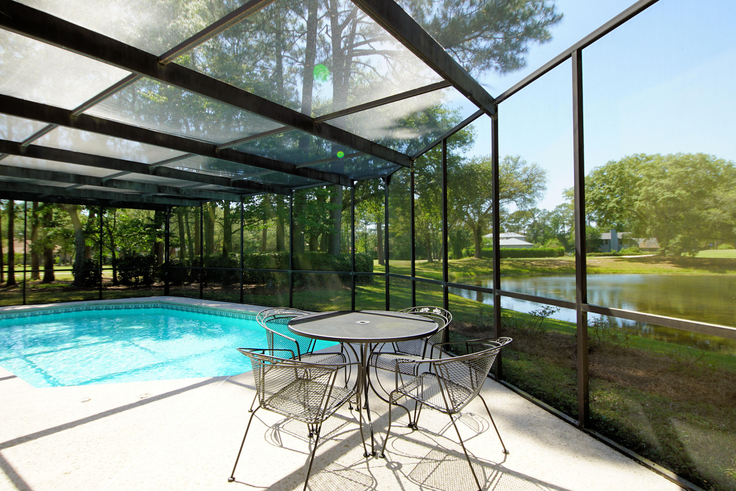 Contemporary brick home with an enclosed pool on the Bluewater Bay golf course overlooking a picaresque lake. You will enjoy the golf course and lake views from the enclosed pool as well as almost every room in this home that was custom built to capture an abundance of natural light streaming through the oversized Peachtree windows and doors throughout. Upon entering this home, you will be stunned by the soaring 28' tongue in groove wood ceiling in the living room that is accented with transom windows. This room also features built in book cases flanking the gas fireplace. This room leads to both the Florida room along the back of the house and the family room that is open to the kitchen. The warm and welcoming kitchen has been updated with new cabinetry and granite counters. For your