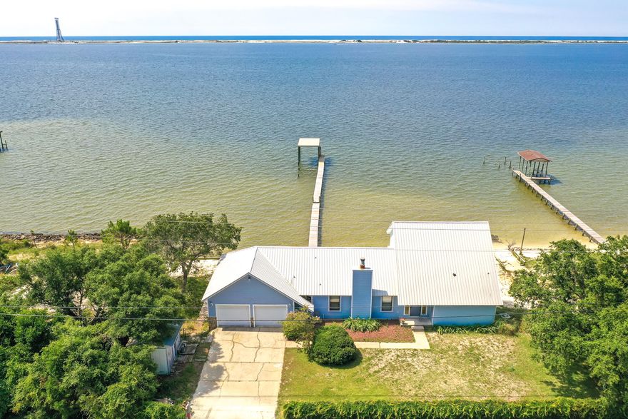 AMAZING VIEWS JUST OFF HWY 98!! METAL ROOF, 225FT DOCK AND BOAT RAMP!! Step inside to discover a home that opens into beautiful views the sound. The main living area features a unique stone, wood burning fireplace and cathedral ceilings. A bonus living area offers additional space for entertaining and features a large window that looks out onto the water. The kitchen has been remolded with new backsplash, quartz countertops, and updated appliances. The 3 bedrooms and 2.5 bathrooms offer plenty of space for family and guests. Spend your days enjoying the view from inside or in your amazing backyard soaking in the sun! This property offers endless possibilities and space for activities, entertaining and relaxing with the covered deck, dock and white sand backyard. Schedule you showing today