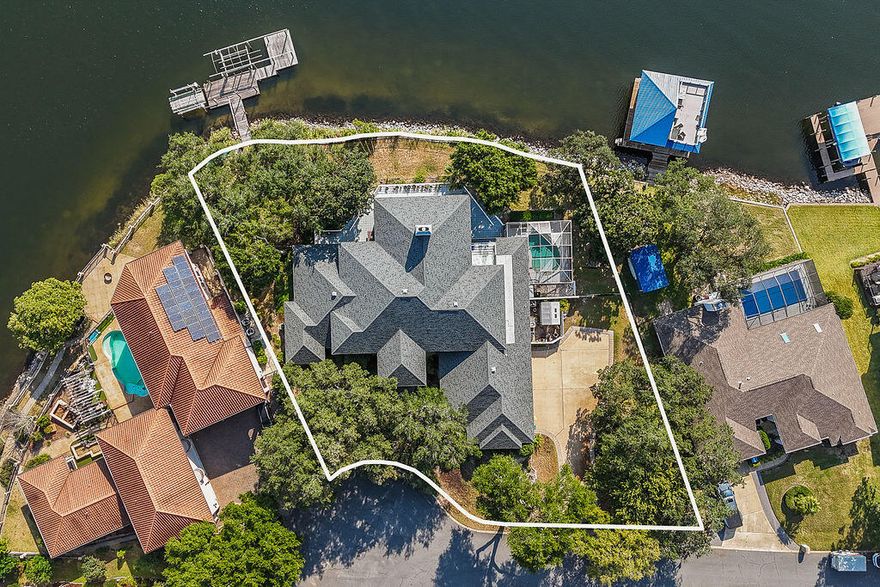 Welcome to your waterfront estate! Located on a double lot in the coveted Lake Pointe neighborhood with 180' of breathtaking waterfrontage, this magnificent residence is more than a place to live; it's a way of life! High and dry in the harbor of Lake Lorraine, with direct access to the bay, this home offers both safety and serenity! Upon entering, you'll be captivated by the sheer size and elegance of this home. Boasting five bedrooms and four and a half bathrooms, this residence offers ample space for family and guests. The primary suite is a sanctuary of its own, featuring serene water views, a private deck, and a luxurious en-suite bath with all the desired amenities.