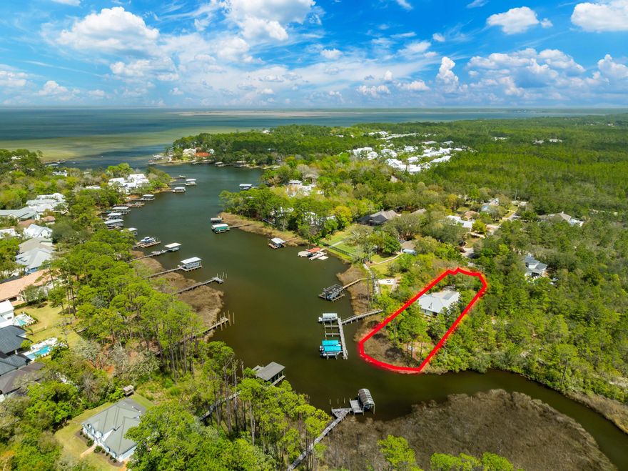 Discover 135 Bayou Point Dr, a beautifully custom-built 3BR/2BA home (2012) featuring 10 ft ceilings and an open floor plan that creates a spacious, airy feel throughout. Situated on over half an acre with 90 feet of waterfront on peaceful Hewett Bayou, this secluded retreat offers direct access to the Bay. The thoughtfully designed outdoor space features lush tropical landscaping, a koi pond, and a cozy deck--perfect for entertaining or relaxing. Additional highlights include a pergola with fish cleaning station and a greenhouse that adds to the property's tranquil charm. A private dock can be permitted or enjoy convenient access to the nearby community dock.