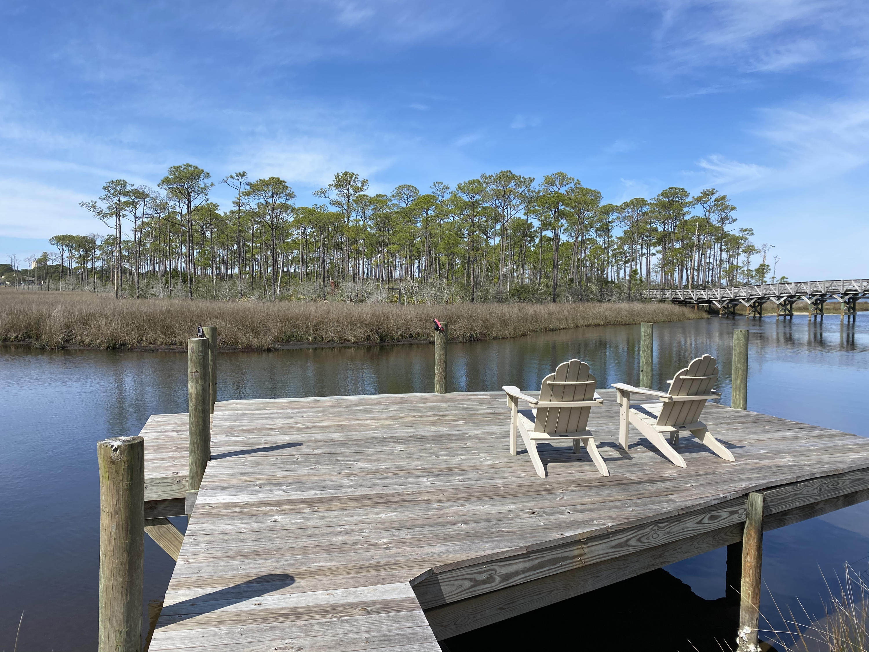 Location, location, location! Rare bayfront cottage with dock in the quaint community of Baypines. Cozy and charming beach cottage with incredible unobstructed views of the bay, Jolee Island bridge, wetlands, and meandering stream. Experience nature at it's finest with the convenience of resort life and all the fabulous amenities exclusive to the resort in this wonderful primary, investment, or second home. Enjoy stunning sunsets over the bay, stream, and resort from the dock as well as from the living/dining area, kitchen, screened porch off the living area, Master Suite, and upper deck off the Master Suite. The community pool is just down the street. Baytowne Wharf, Baytowne Marina, Sandestin's Tennis Center, and Grand Boulevard are a quick golf cart or bike ride (golf cart included!).