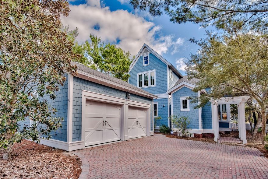 Forget cookie-cutter architecture. This charming coastal cottage in WaterSound Beach has instant curb appeal with its Gulf-blue shingle-clad exterior behind a white picket fence. A paved driveway sweeps up to the two car garage terminating in a footpath to the front porch and entrance. Step inside to find gleaming wood flooring, traditional paneled wainscoting, new lighting and a warming fire in the fireplace. Filled with artworks and handpicked accents, it's a room for sharing happy times with family and friends. The open floorplan flows from the well-lit dining area into the gourmet kitchen. Chefs will look with envy at the range of white Shaker-style cabinets, stainless appliances and black granite counters.