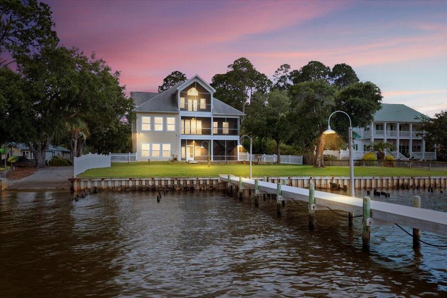 Private Boat Ramp, 1.3 acres, Elevator, Dock, Lift, No HOA, 120 feet or shoreline- This 4,080 sq ft waterfront home has it all. 5 bedrooms, 3 full bathrooms, and versatility for multi-generational living or income potential.A rare private on-site boat launch and flow-through dock with boat lift make jet skiing, boating, and waterfront fun effortless. The dock also features a covered entertainment space with electricity, water-misting, plumbing, and security cameras--perfect for cleaning fish or sunset gatherings. Designed for comfort and accessibility, the home includes an elevator servicing all three levels. The lower level functions as its own living quarters with 2 bedrooms, a full bath, a kitchen, and living area, making it ideal for guests, rental income or in-laws. 
The middle level encompasses 2 more bedrooms, a full bath and a versatile entertaining space with an open concept design. The bright kitchen boasts gourmet appliances and spacious granite counter tops. A generous island with seating for six ensures the chef stays at the heart of every gathering. A modern, elegant fireplace anchors the living room, creating a warm and inviting spaceyet the expansive views of East Bay, visible across the entire back of the home, remain the true focal point.
The top-floor Owners suite is a true sanctuary, offering views of both the private estate and the bay. Enjoy three stories of screened porches that stretch across the rear of the homeideal for dining al fresco, morning coffee, or simply watching dolphins at play.
Outdoors, you'll find the beautifully maintained grounds with plenty of space for a pool. The home sits directly on the paved multi-use path that connects Gulf Breeze and Navarreperfect for stroller walks, jogging, biking, and golf cart rides. This property in the well maintained community of Lagniappe Beach has no HOA. 
Whether you're enjoying nature, or launching onto the water, this rare gem delivers the ultimate in waterfront living.