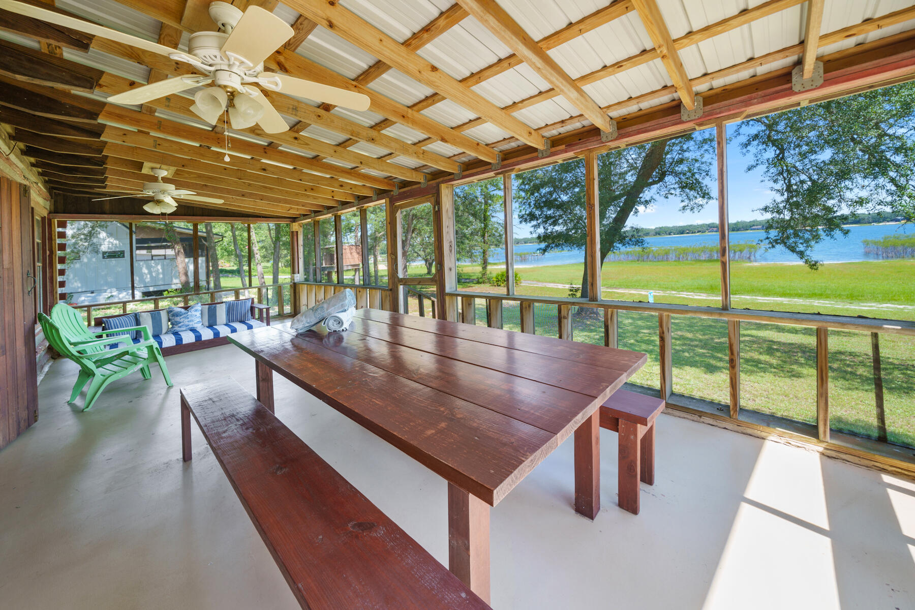 Get ready to make incredible family memories at this log cabin sitting on two lakefront lots with a million dollar view! White Western Lake is one of the most beautiful spring-fed lakes in the area, and while it's only a short drive away from the shops and restaurants of Lynn Haven and Panama City, and is just a 30 minute drive to the world-famous beaches of Panama City Beach, this waterfront location is country living at its finest. Enjoy starry skies overhead, easy lake access for swimming, boating and water skiing, and nearly 600 feet of safe, wide open grassy area between the cabin and the clean, clear water of the lake. The cabin itself was constructed from heart pine logs harvested locally when the house was built in 1960, and are strong and sturdy -- like the old saying goes, ''They don't make them like this anymore!'' The interior of the cabin is a wide open floor plan, with a beautiful wood burning fireplace, with a high vaulted tongue and groove ceiling, with wooden beams and a crystal chandelier adding to the cabin's rustic charm. The smooth poured concrete floor is maintenance-free (perfect for lake life), and two bedrooms, a bonus room, and a walk-in closet line the back wall of the lake house. A wide, screened-in porch stretches the entire width of the front of the house, taking in the breeze from the lake, while the lake views are enjoyed from both the porch and the open floor plan of the living room and kitchen. The double doors that open from the living area to the porch are incredibly solid and fit perfectly, and the original windows throughout the house fit securely while opening and closing easily (again, that classic, quality craftsmanship). Currently it's ready to host summer camp-style get-togethers and overnight trips, or with a little work you could make this your year-round residence. The seller is open to including the bunk beds and queen sized bed, as well as various other furniture and accessories so you can start enjoying lake life and making family memories right away! The White Western Beach Home Owner's Association maintains the road and has an extremely low annual fee (only $47 for the year in 2024). This friendly waterfront neighborhood consists of only 11 houses which are used as weekend family retreats or full time residences.
