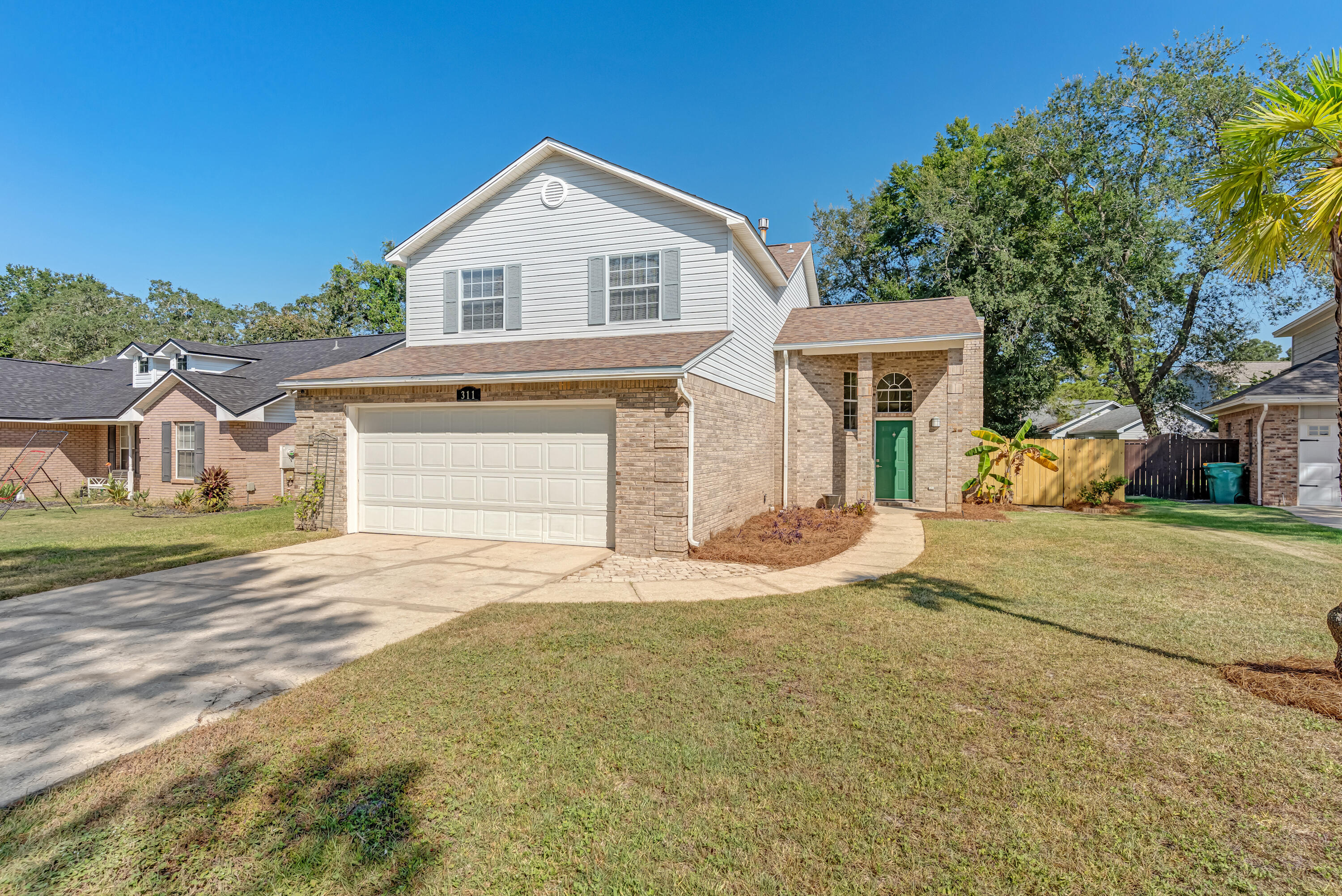Welcome to Parkwood Place at Bluewater Bay! This charming two-story home offers 3 bedrooms and 2.5 baths in a highly sought-after neighborhood close to schools, shopping, and the beaches of the Emerald Coast. Upon entry, you'll find a spacious living room featuring a gas fireplace and unique porcelain tile flooring that flows into a formal dining area with a bay window. Just beyond, there's a cozy second living space with a convenient half bath, laundry area, and access to the two-car garage. The eat-in kitchen connects seamlessly to this second living area and includes a dedicated breakfast nook window, solid oak cabinetry, newer stone countertops, and black appliances, providing ample space for cooking and entertaining. Upstairs, all 3 bedrooms feature light oak-look laminate flooring and lots of natural light. The primary suite boasts a large whirlpool tub, a separate walk-in shower, and extended dual-sink vanity, and a spacious walk-in closet. The 2 additional bedrooms include ceiling fans and share a full guest bath located in the hall.
Outside, enjoy a fully fenced backyard with a small patio, mature shade trees and a green lawn space, perfect for relaxing or entertaining. Additional highlights include fresh paint throughout, a 2 car garage and a prime location within Bluewater Bay's Parkwood Place community.