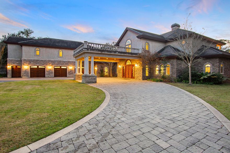 A rare opportunity to own a 2.5-acre estate on the water in a coveted location with no HOA, no restrictions. The live oak-shaded private entrance, past a fenced pasture and horse stable with two stalls and tack room, gives way to a circular drive with covered porte-cochere entrance. Plenty of parking for guests or nautical toys in the 3.5-car garage or the pavered drive. Hand-carved double teak doors open to a grand foyer with sweeping staircase and whitewashed Craftsman-style columns. Just beyond the entrance and past a chandeliered sitting room with wood-burning fireplace is a 2000 sq ft limestone patio, an expansive lawn, and 200 linear feet of shoreline on Hewitt Bayou with a private dock and covered boatlift.  (Continued...)