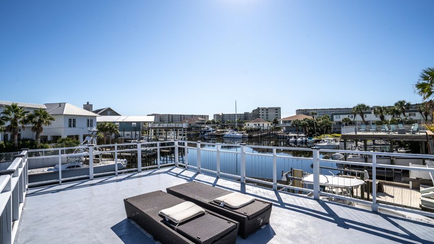 Live life on the water! Imagine fishing on the Gulf or going to Crab Island all within a few minute boat ride from your private dock & massive covered boathouse that can fit up to a 35ft boat. Entertain or get some sun on the huge deck overlooking the canal. Beautiful Gulf beaches across street with private access. This townhouse has been meticulously maintained for the past 10 years.  Plenty of room to sleep a large family or make a great investment property with every bedroom having private bathrooms. Once inside, granite counter tops, S/S appliances, Open concept with tall tongue & groove, cypress beam ceilings. No Bldg HOA! Not a rental but projected revenue around 65K.  Buyer to verify all dimensions. Seller is a licensed realtor in FL.