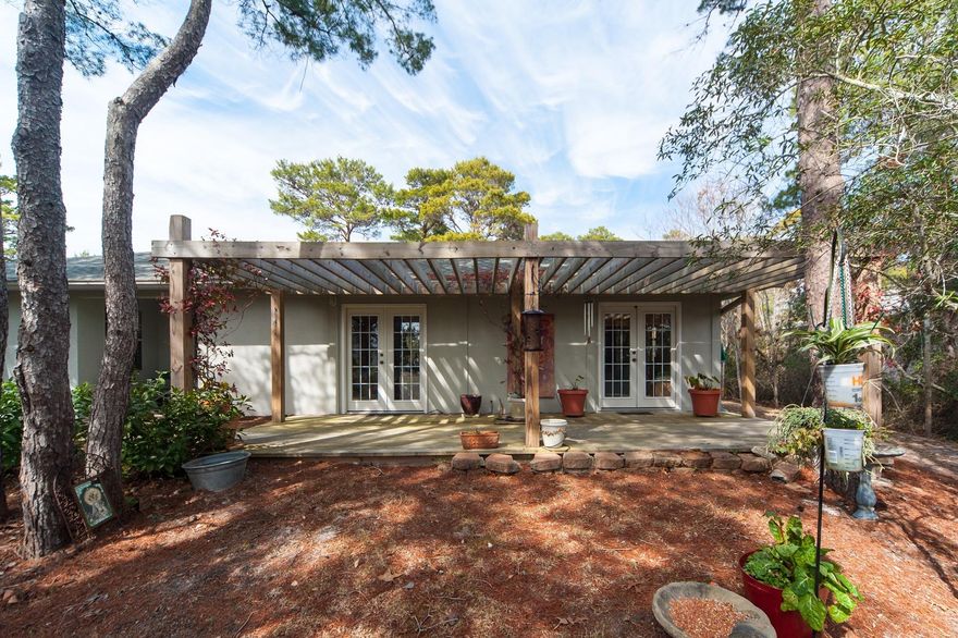This secluded single level home on a large, half acre lot is located in The Pines of Blue Mountain Beach off Scenic Highway 30A with room to add a pool, additional square footage or even a carriage home. Beach access is close by, as are many local shops and eateries that include health food store, bakery, and bike shop. Warm Saltillo tile floors carry throughout the kitchen, adjacent dining area with fireplace, and light-filled living area. Granite counters appoint the kitchen, and its wraparound bar seating allows guests to remain engaged with the host while entertaining. Off the living room and master bedroom is an expansive arbored deck overlooking the naturally landscaped yard. Cruise east along 30A's paved trail to Seaside, or west towards Gulf Place.