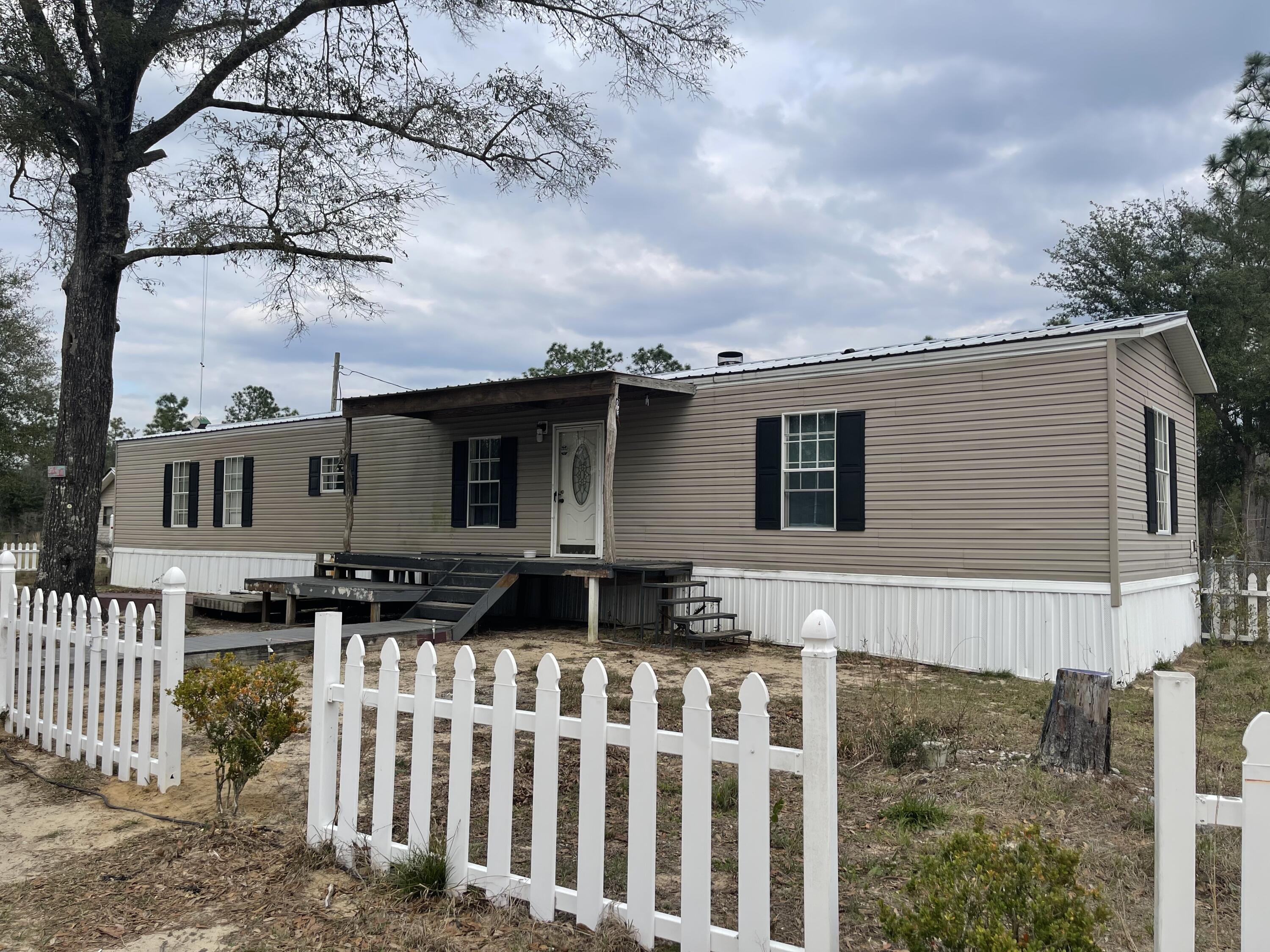 Private Country setting 10 acres high and dry, peaceful and secluded. Lots of possibilities. Larger style carport provides a covered area for parking or a great entertainment spot or plenty of room for outdoor activities. Additional building which was used as a rental property, but can be for creative use. The 2008 Mobile Home split floorplan has 3 bedrooms, 2 baths, wood burning fireplace, stone accents and open kitchen/living/dining with front and rear entrance. Outdoor spaces are enhanced with decks and picket fence to create a lovely lawn and garden or put another house. Cash Offers Only.