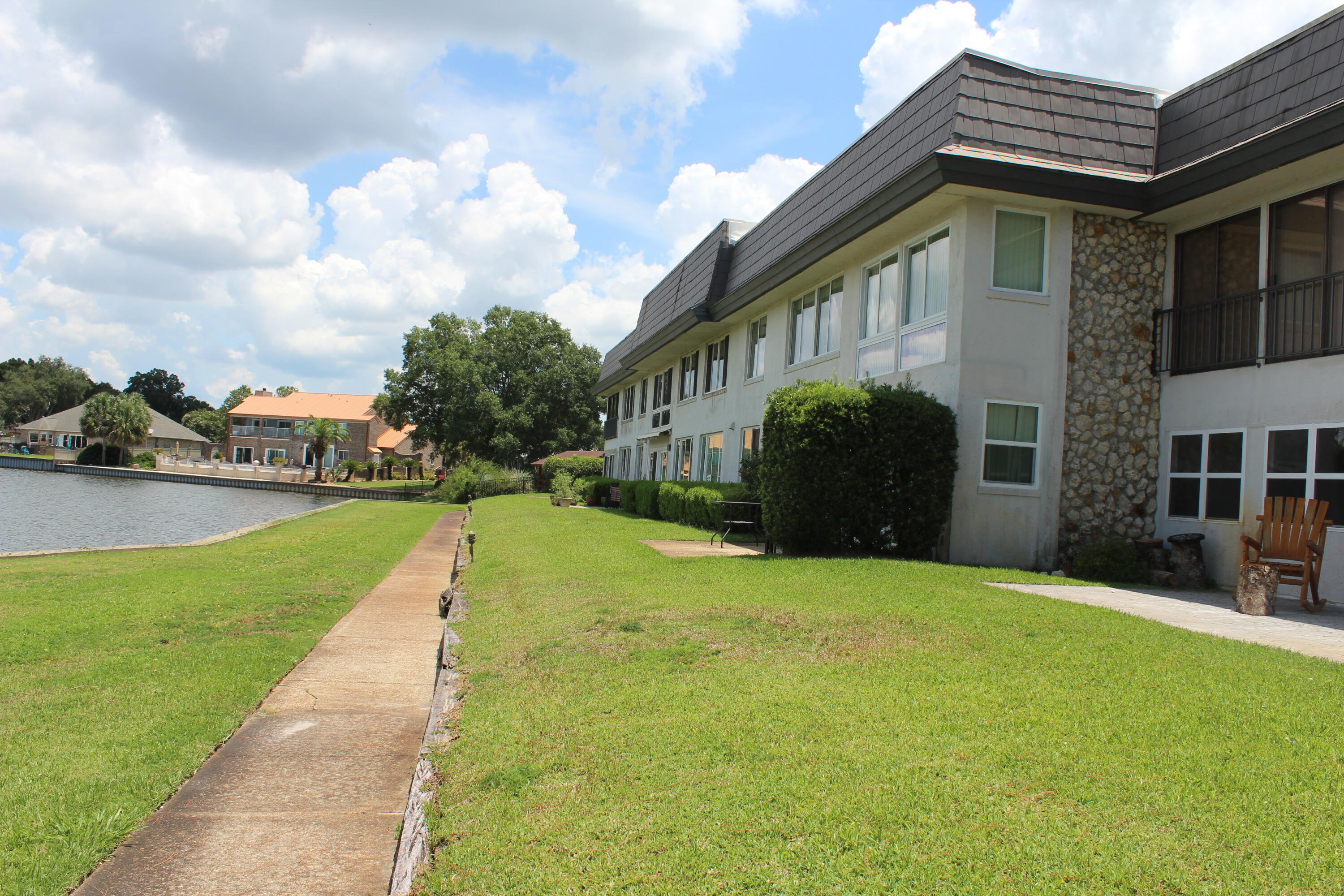 A magical setting in the middle of single family home setting on a lake. Unit is on the 2nd floor with magnificent views from the entire front of the condo windows. The patio has been enclosed adding 150 SF of living for a den/office/formal dining or morning room. 2 large bedrooms each with a bathroom. Washer dryer hookup. A one car garage with shelving and a work area. All tile and LVP flooring with fresh paint and a wet bar off the living room. New roof & seawall in 2022. Playground across the street. Pets limited to 20 pounds. The lake is also connected by a canal to Lake Joann and the fishing is good. No gas motors only electric. There is a charcoal grill area. Quick occupancy and must to see.