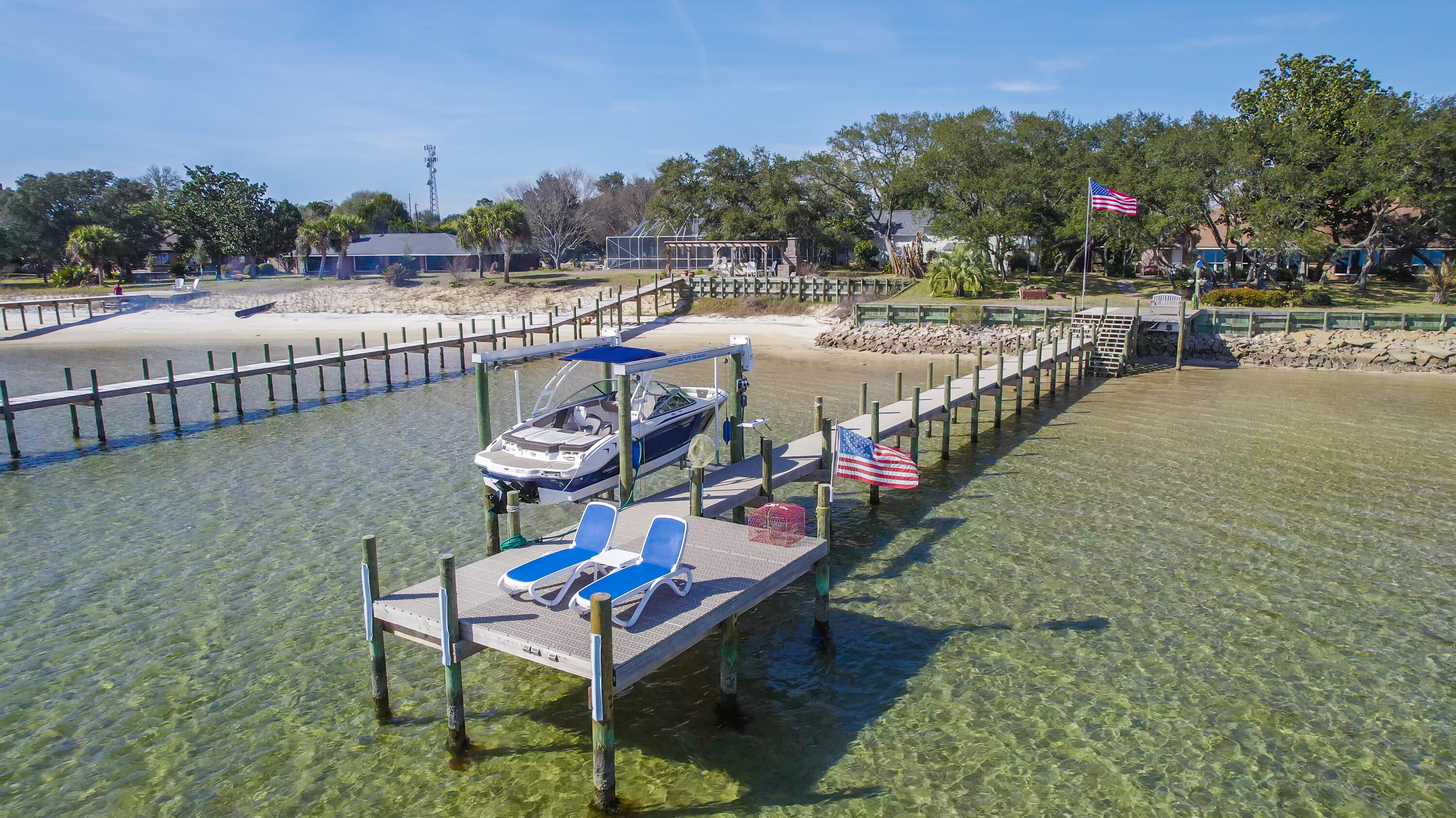 Introducing the ultimate waterfront paradise! Located in a desirable X flood zone, this home boasts 100 feet of waterfront with an 8,000 lb boat lift and a brand new flow through dock. Enjoy views of the sound from every angle as you make your way to one of several seating areas overlooking the water. This 4-bedroom, 3.5 bathroom home has been beautifully renovated throughout. From its travertine tile and LVP flooring to its KraftMaid custom cabinetry and quartzite counters in the kitchen, no detail has been overlooked. And speaking of kitchens, this one comes fully equipped with high end Bosch appliances including a built in espresso machine and two under counter refrigerators (one with ice maker) along with a 48 inch gas cooktop with pop up vent to outside for those gourmet chefs out thereThe split floorplan offers privacy for each bedroom while still allowing easy access between them. The primary suite enjoys large windows offering stunning views of the sound along with cedar lined closets featuring built in closet kits for additional storage space. The primary bathroom is sure to impress featuring a separate tub and grotto style showerthe perfect retreat after a long day on the water! For added living space there's also a bonus room above the garage complete with ?? bath and closet that's heated/cooled.  Outback you'll find an inviting paver patio & walkway leading directly down to your private dock that is great for entertaining or relaxing afternoons spent listening to waves crash against shoreline below.