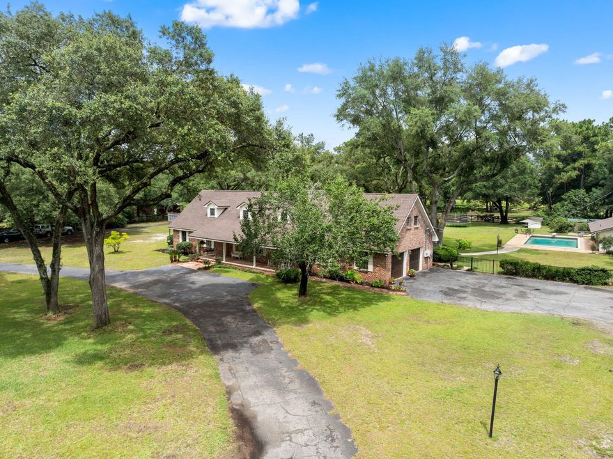 This unique property is in the heart of town but feels like you are out in your own oasis! Once inside this beautiful 2 story brick home with a circular drive you will find travertine floors, an updated kitchen with stainless steel appliances, a separate dining room and a wood burning fireplace in the living room. There are 3 bedrooms and 2 full baths downstairs. As you begin upstairs, you have a private bedroom suite to the right with a full bath and outside deck access. Across the hall is the main bedroom suite complete with a large bathroom, double vanities, large walk-in shower, and a jetted tub that looks over your private acreage. Off the rear of the main bedroom is a walk-in closet with enough space for storage, an office or a personal gym. The property has a tennis court, in ground Gunite Pool, sauna, and a separate guest house that has a full bath and kitchen (use this as a mother-in-law suite, studio or to generate some income as an Airbnb with its separate gate entrance for access). The back yard is fenced with an 1,856-sf steel framed barn and a separate Run-In. There is also a well Pump for lawn Irrigation. The main house, irrigation wellhouse and pool/guest house all re-roofed in 2021.  A new septic tank and fill lines were replaced for the main house June 2025. New tankless hot water heater for main house 2023, Main house had both HVAC's replaced in 2021 (2nd level) and 2024(main level). Pool house HVAC replaced in 2025. Everything has been updated, and this gorgeous home is ready for you to move in!  