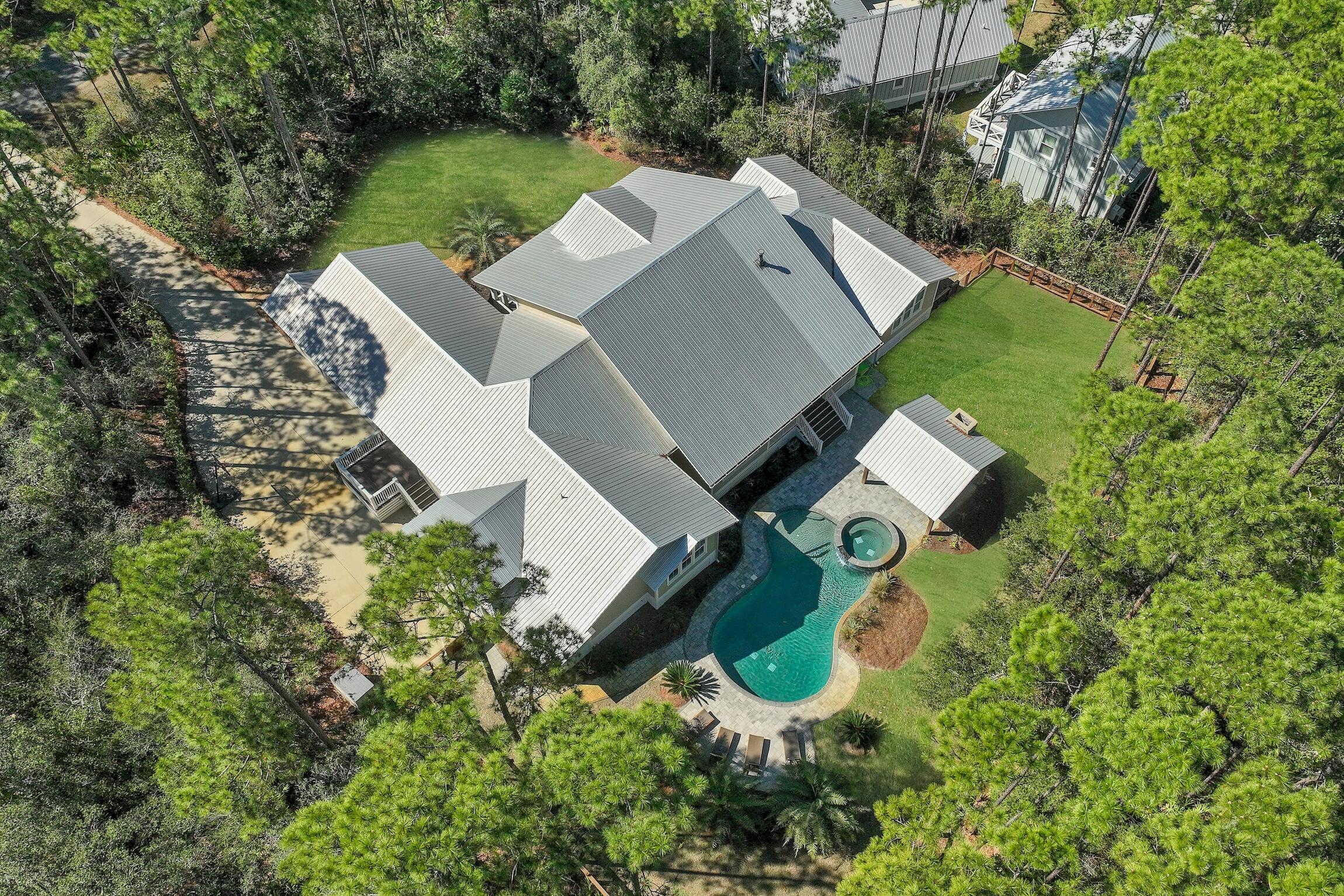 Nestled within the serene confines of THE WOODS, a tranquil bay-front community in Pt Washington, lies 164 North Brookwood Drive. This custom home, set upon a private wooded 0.6-acre estate, offers a seamless blend of modern comfort and natural beauty. Boasting over 3,900 square feet of single-story living space, its design emphasizes both luxury and practicality.Step inside to discover a thoughtfully crafted interior, featuring a spacious owners' suite, a versatile split floor plan, and the cozy ambiance of a fireplace. The heart of the home is its expansive kitchen, adorned with double islands, catering to both culinary enthusiasts and gatherings alike.Outside, a backyard paradise awaits, complete with a refreshing pool and spa,