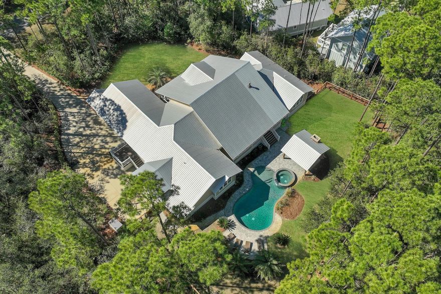 Nestled within the serene confines of THE WOODS, a tranquil bay-front community in Pt Washington, lies 164 North Brookwood Drive. This custom home, set upon a private wooded 0.6-acre estate, offers a seamless blend of modern comfort and natural beauty. Boasting over 3,900 square feet of single-story living space, its design emphasizes both luxury and practicality.Step inside to discover a thoughtfully crafted interior, featuring a spacious owners' suite, a versatile split floor plan, and the cozy ambiance of a fireplace. The heart of the home is its expansive kitchen, adorned with double islands, catering to both culinary enthusiasts and gatherings alike.Outside, a backyard paradise awaits, complete with a refreshing pool and spa, cabana and fireplace, all enveloped by lush professional landscaping. This tropical oasis provides the perfect setting for relaxation and entertainment, offering a retreat from the bustle of everyday life.

Residents of this idyllic abode enjoy the added amenities of THE WOODS community, including a neighborhood trail and a private dock on the bay, fostering a sense of connection with nature. Furthermore, its prime location ensures convenient access to nearby schools, shopping destinations, and the pristine white sand beaches of 30A, promising a lifestyle of ease and enjoyment.