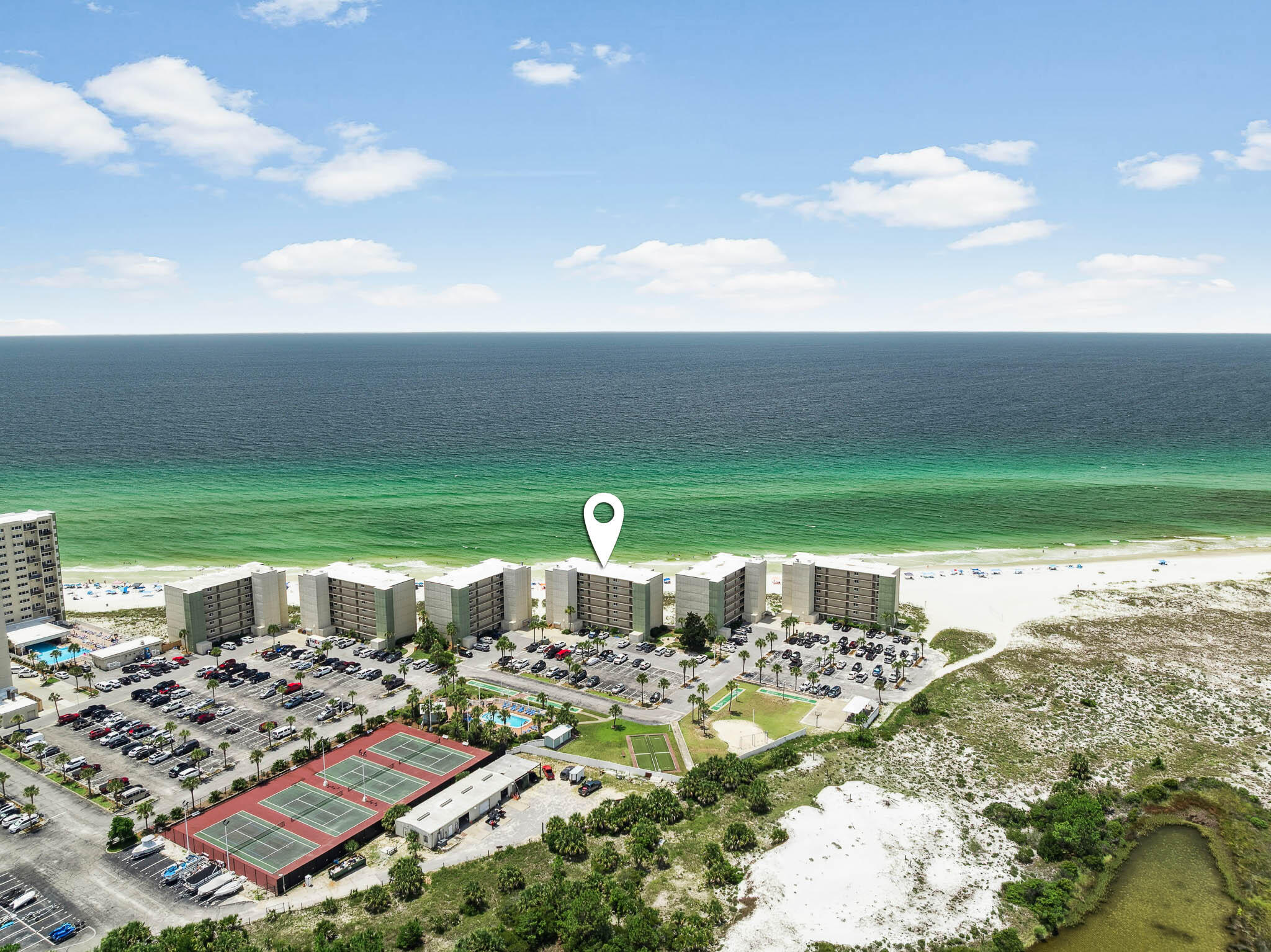 Whether you're looking for a smart investment, a nostalgic beach escape, or just a low-drama slice of the Gulf Coast, C2-502 delivers. This is one of those condos that doesn't come around often - because the people who buy them, keep them. Located on the 5th floor of the mid-rise building at Pinnacle Port, Unit C2-502 offers panoramic views of the Gulf and a floor plan designed for easy vacation living. This condo has been carefully maintained and thoughtfully cared for by longtime owners, with a level of attention that's hard to find in vacation properties. The open-concept living and dining area is filled with natural light and opens to a private balcony with stunning Gulf views. The kitchen is fully equipped and thoughtfully laid out, with a breakfast bar that flows into the main living space. The primary bedroom includes an en suite bath and panoramic view of the beach, while the second bedroom offers privacy and flexibility for guests or family.
This unit has functioned as a successful vacation rental, grossing $30K-$35K annually over the past two years. It's been entirely self-managed - no Airbnb or VRBO listings - providing a strong foundation and even stronger potential for future income.
Pinnacle Port is a gated beachfront community tucked between the Gulf of Mexico and Lake Powell, offering a wide range of amenities: indoor/outdoor pools, tennis courts, boat ramp and slips, fitness center, playground, picnic area, and easy access to Carillon Beach and nearby 30A.