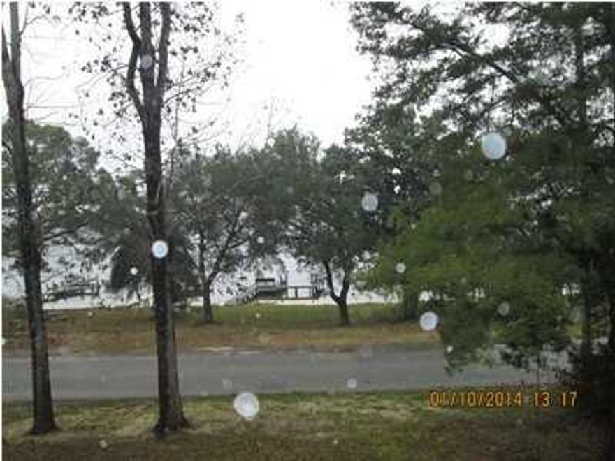 Very nice home with Waterview of Tom's Bayou from Living Room, Kitchen and Master Bedroom. Deep water dock located across street. Spacious covered porch on front of house to sit out and enjoy views of Bayou. Entrance Hall with Wood Paneling and Wood Flooring. On left is Large Kitchen with 6 Burner Jen Aire stove, separate over. Large sit at counter/breakfast area. Wood Flooring. Dining area is Spacious, carpeted, has wood burning Fireplace, wet bar area. Two doors open to Garage area. Very Spacious Family room, Carpeted, sliding glass doors on one side open to Hallway to Two bedrooms downstairs that share a full bath. Double Vanity, Separate Shower, Whirlpool Tub. Both have wood flooring. From Family Room, doors open to Large room that could be Living room, den, sitting room, etc