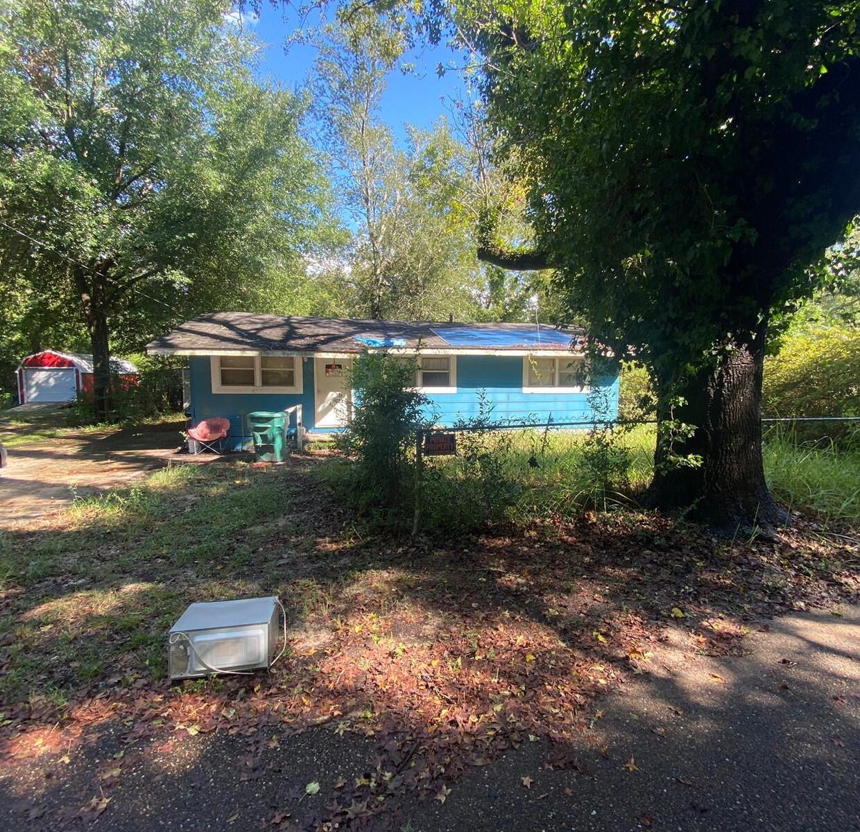 This charming 1040 sqft property features a spacious enclosed utility room and a convenient concrete driveway. The kitchen boasts homemade cabinets. While the home needs a new roof and the floor is uneven, the foundation and structure are sound. Has wall units for heating and cooling.