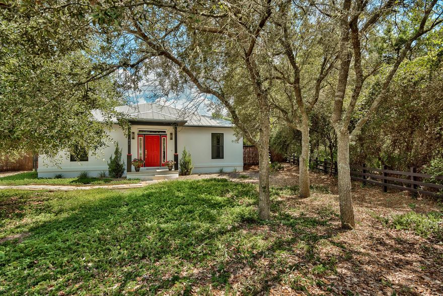 42 Seabreeze Way is located at the end of a quiet cul-de-sac, and boasts a large, pie-shaped lot. The parcel offers many large, mature trees and shrubs, which give the home a comfortable and private feeling. The home was constructed with a system of formwork for reinforced concert and rigid thermal insulation, known as insulated concrete form (ICF). The bright white stucco exterior is a very clean and inviting style, juxtaposed with jet black trim detail, and accented with a vibrant red front entry door. Red is the feng shui color for prosperity and abundance. The single story home opens to vaulted main living room, which divides the bedrooms for a spacious split floor plan. The interior finishes are clean and minimalist. An expansive kitchen and bar are finished with dark, stately granite