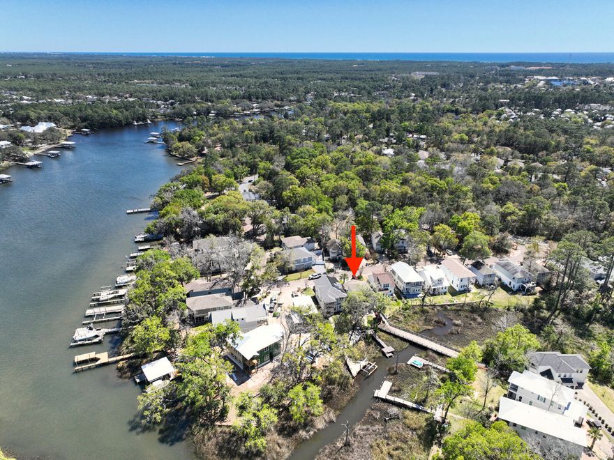 This is the UNICORN! Protected, waterfront custom home with your very own dock to access the wonders and adventures of the Bayou. This two story Florida Cottage style home boosts 1830 square feet with 3 bedrooms, 3 full bathrooms tucked in the sought after Sacred Oaks subdivision with beautiful Live oak trees and features underground utilities, brick paved street and community boat dock. The foyer welcomes raised ceilings into an open flow with kitchen, living and dining with center island granite countertops and custom cabinets with subway tile backsplash.  Generous pantry with plenty of space for storage, plus the walk-in laundry room with wash sink. Step outside to the 1st of two patios... one covered and screened to be used in all weather and the other a beautiful brick paver patio to