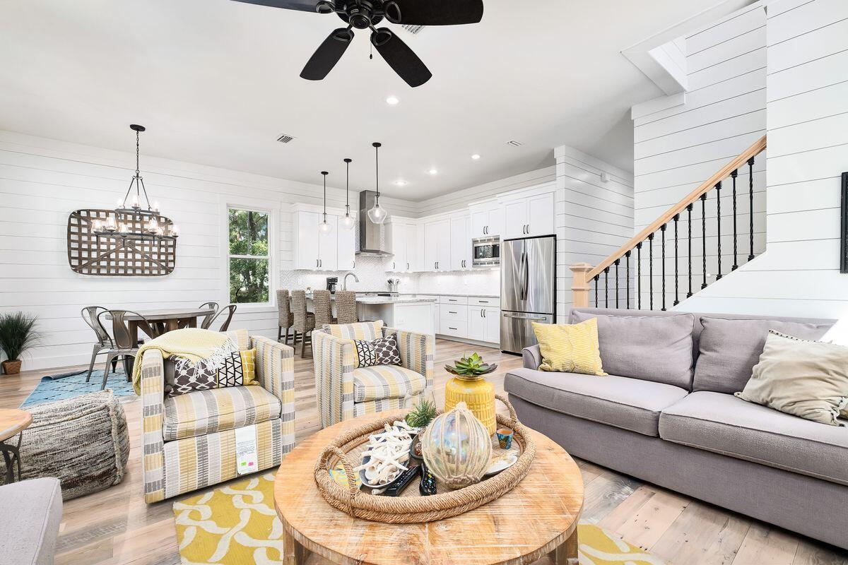 Steps to WaterColor, Seaside, and the beach, this luxury home is enviably located in the gated and lush sanctuary of The Hammocks at Seagrove. The long paved driveway winds through mature greenery to the shady front porch providing a sense of privacy and seclusion. Step inside and admire the distressed hardwood flooring enhanced by 10-ft. ceilings and ample natural daylight. White shiplap walls and panel doors convey a sense of durability. The hallway opens into a contemporary open kitchen with sleek quartz countertops, Bosch appliances, a gas range and generous breakfast bar. The modern living/dining area opens directly onto an expansive screened deck.