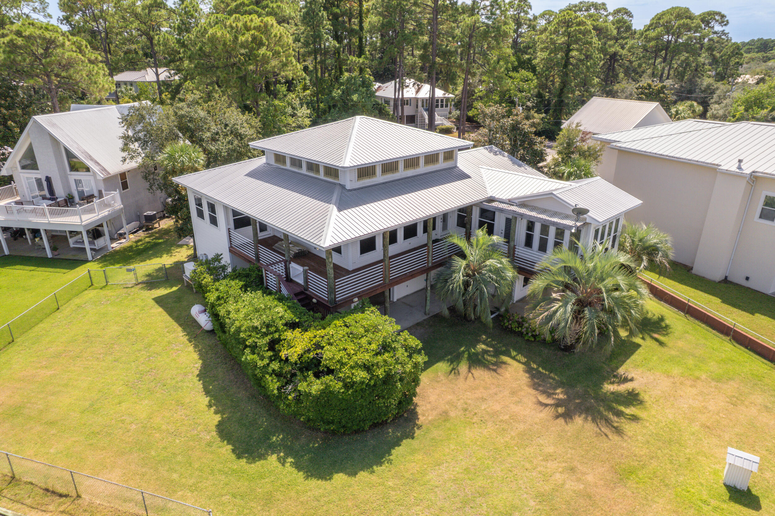 Live the dream in this spectacular Bay front oasis thoughtfully positioned on a rare double lot, where dazzling sunrises and sunsets light up the sky as dolphins glide past. Wraparound porches and patios offer breezy, shaded spaces to relax or entertain in true coastal style. The sun-filled main level features an open great room with panoramic views and access to a covered deck. An elevator makes daily living effortless. Private lower-level suite boasts a full kitchen/bath, spacious bedroom, and private patio--perfect for guests or extended family. A deep two-car garage with rear door offers ample storage for kayaks, paddle boards, or golf cart, plus workshop space. This home also has an emergency generator. Private dock features two boat lifts, including a covered lift with remote, a walkaround dock, and a fish cleaning station for the catch of the day. Paradise awaits!"