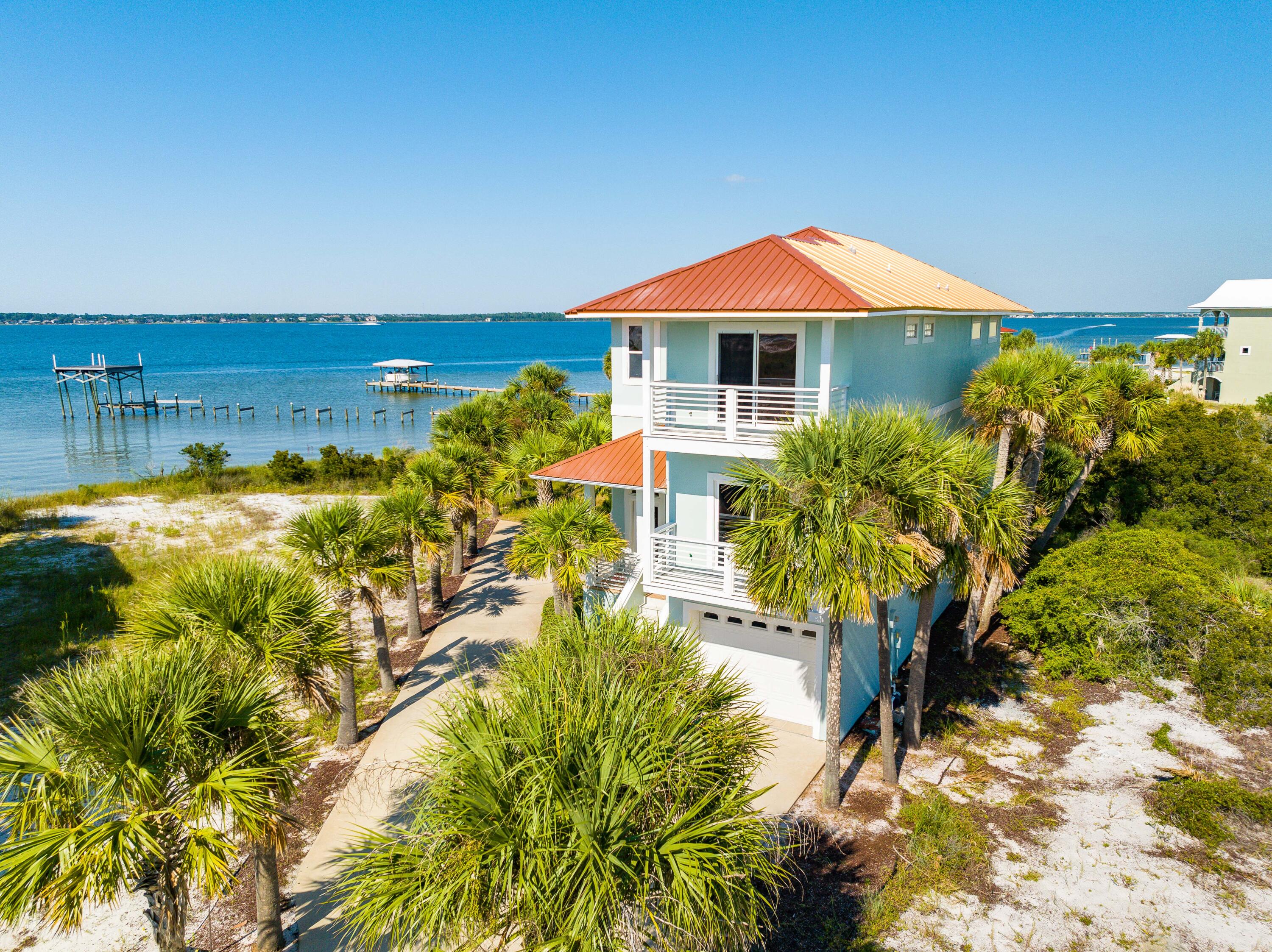 Reduced $25,000. In gated community of Caribbean Isle this 3 bed 3 bath is perfect for entertainment and relaxation. This home boasts heavenly Sound views, is situated between 2 empty lots, and backs up to open space. Upon entrance to the open concept dining room and kitchen, you are greeted with an abundance of natural light. The kitchen features stainless steel appliances and ample space for storage. The living room adjoins the kitchen and dining room, and is spacious with 20 foot ceilings. Unique architectural details including curved archways and an indoor balcony off the primary bedroom set this house apart. Glass sliding doors open to the oversized wrap around porch overlooking the emerald waters of the Santa Rosa Sound; the perfect place to enjoy a morning coffee or an evening drink