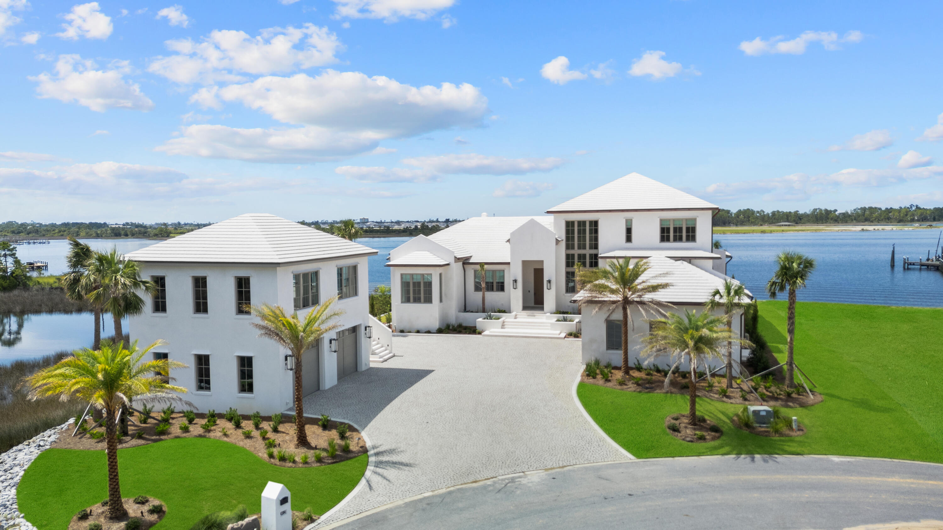 This is a WATERFRONT home that transcends expectations and delivers privacy over prestige--exuding quiet, effortless luxury. Tucked away on a private island of 381' of shoreline in Panama City, Florida, this 2025 newly constructed residence is more than just a home...it's a legacy. A rare blend of architectural brilliance, natural beauty, and elevated craftsmanship, this estate redefines coastal living. Designed by Wes Seaborn, built by McIntosh-Myers Construction, and curated by Lori Faison Interiors, every element was intentionally crafted to support a lifestyle of beauty, comfort, and refinement. The design is rooted in organic minimalism, elegant in simplicity, yet rich in warmth and texture. A 12' impact-rated mahogany door opens to a soft palette of Venetian plaster, shellstone, and white oak select throughout. Light dances across barreled plaster hallways with fused-in lighting beneath. It's a quiet symphony of detail. Subtle, yet unforgettable. The vaulted living room is clad in white oak select with a fluted plaster fireplace and Nano doors that open to a sprawling covered lanai. The adjoining dining room, wet bar, and open kitchen invite gatherings, centered around paneled SubZero and Miele appliances, concrete countertops with fused-in sinks, and custom EF San Juan cabinetry. A remarkable scullery and discreet storage keep the space functional yet clean, perfect or entertaining or daily life.
Spanning 5,364 SF of heated/cooled space and 8,543 SF under roof, the main residence exudes a highly desirable floorplan. All bedrooms enjoy breathtaking panoramic water views. Offering seamless Gulf access just 10 nautical miles away, without idle zones slowing you down and pure Bay views. At 14' elevation and built of poured solid concrete, this home is as resilient as it is beautiful.
The private primary suite is its own tranquil escape, accessed through a barreled, Venetian plaster backlit hallway. Inside, you'll find motorized drapes, a beverage fridge, and a steam shower and soaking tub that will take you straight to the spa. Step through to your private lanai and fireplace for pure relaxation.
With four spacious bedrooms, four full en suite baths, and two half baths, there's space for hosting without compromising privacy. A dedicated home office wrapped in oak and plaster, oversized laundry with dual washers/dryers, and a thoughtful mudroom with custom lockers make daily routines effortless. Step outside to the covered lanai and unwind by the outdoor fireplace or summer kitchen. The negative-edge pool is a work of art fused with design. Custom tile-lined, stone-surrounded, and built with a chiller/heater, trough-style drains, and no skimmer for a clean, seamless finish.
But the performance is just as impressive as the design. Featuring a 4-car garage and built atop a two-way slab, the structure features poured CMU block, a concrete roof, copper gutters, Andersen impact-rated windows/doors, and a reinforced safe room with poured concrete and rebar. A 500-gallon buried propane tank powers key systems, supported by three HVAC units, three tankless water heaters with circulating pump, a generator-ready transfer switch, and a deep irrigation well.
Every detail reflects a level of quality rarely seen, fused-in window and baseboard trim, concealed backlit air returns, modern custom Boyd lighting, solid concrete countertops, and custom 8' solid doors. The Lutron lighting system offers full customization for every mood and moment. For future expansion or guests, the detached carriage house provides 830 SF of space already roughed in with plumbing and electrical, ideal for a guest loft, art studio, or wellness retreat.
This is more than a residence. This home is a legacy. It's a peaceful sanctuary where design meets intention, where the only thing more breathtaking than the architecture is the view. If you've been searching for a home that's as extraordinary as the life you want to live, you've just found it.