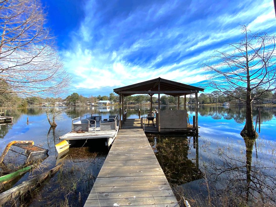 Large corner lot lake house on beautiful lake Juniper. The house is a 1965 single wide mobile home with a large addition that includes a wrap around porch overlooking the lake. The house has been wrapped in split log type siding that gives it that cabin look. There is a covered dock with fish cleaning area and an eating area The property is fenced in with a 6'' wooden privacy fence. Large storage shed in the back yard. The two car detached carport is on a paved drive. Interior could use some work.