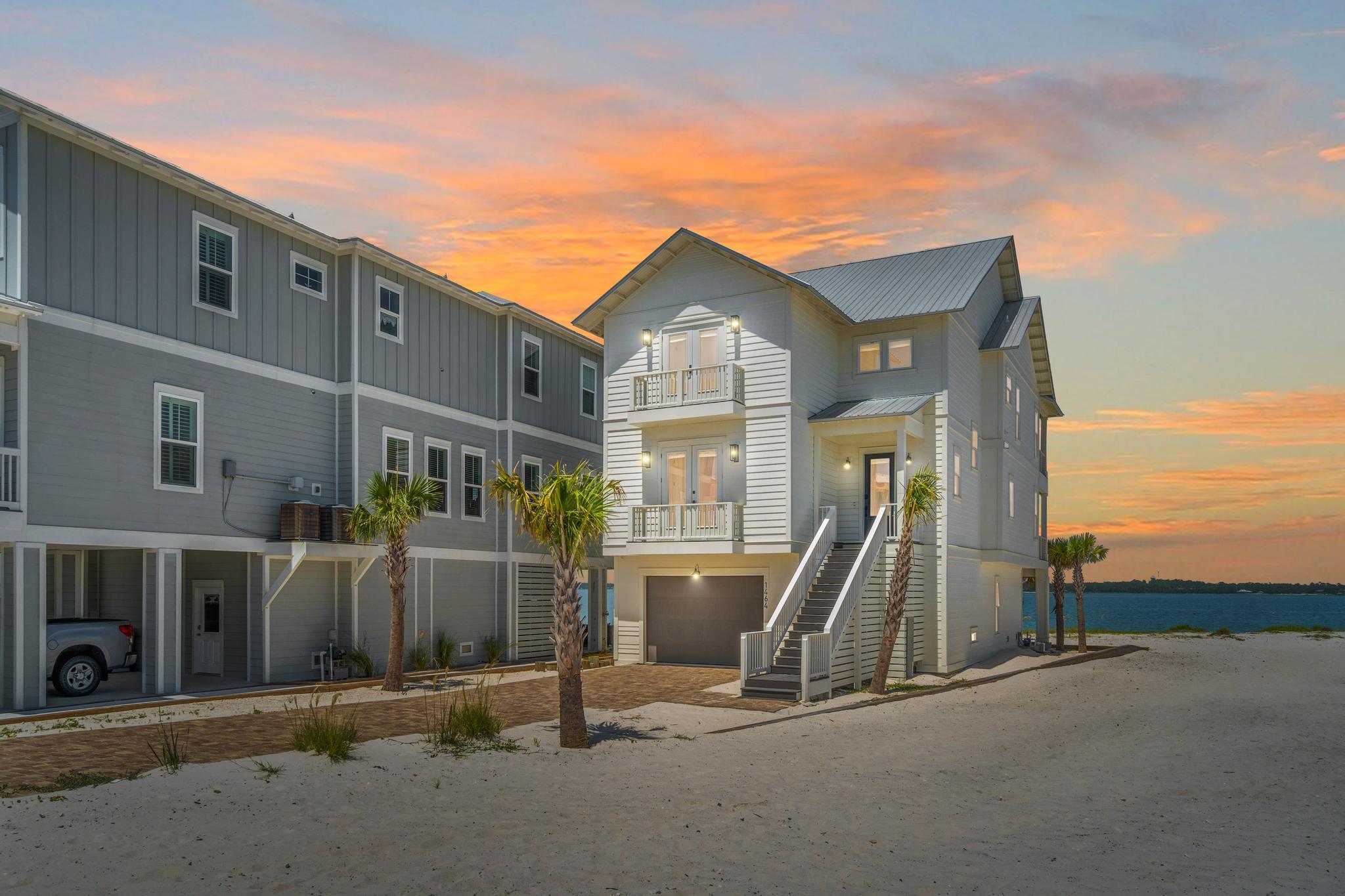 STUNNING waterfront custom home on Navarre Beach. Located in a quaint gated community, this beautiful home sits on one of the few direct Sound front lots in the neighborhood and offers 110 ft of water frontage. Enjoy the best of both worlds living directly on the Sound while just a short walk, bike or golf cart ride to the beach. Upon entering the home, you will notice the high ceilings, gorgeous distressed pine floors and chic beachy decor. This home features 5 bedrooms with 5 ensuite baths plus an additional half bath. You will find 2 gorgeous waterfront primary suites on the first and second living levels with large soaking tubs, seamless showers and dual vanities.