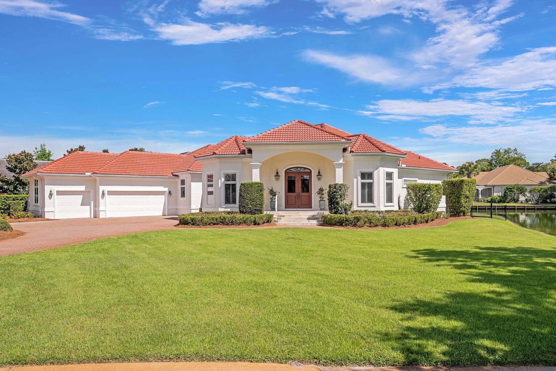 Presiding over a lakefront lot of almost a half-acre, this magnificent Mediterranean-style home has many enviable features and updates. Beautifully architected on the outside, the home revels in its waterfront position with stunning views from most rooms in the house. The broad brick-paved driveway sweeps up to the three-car garage with ample space to accommodate cars and a golf cart. Shallow steps lead up to the imposing front entrance, with tall columns making a grand first impression. Leonardo travertine tile leads to the double door entrance, which opens into the first of two spacious living areas. Brazilian hardwood flooring graces each area, including the open chef's kitchen, which enjoys impressive views. Custom cabinetry, granite countertops, and stainless steel appliances make this a well-appointed space. Keen cooks will note the six-burner gas range/oven, dishwasher, wine cooler, and a pantry for storing additional items neatly out of sight. There's a breakfast bar as well as a dedicated breakfast nook for starting each day with the best views. Designed for entertaining, the kitchen opens into a family room with a fireplace, providing a cozy ambiance. This irregular-shaped room looks out directly onto the screened pool and spa, which in turn overlooks the peaceful lake. All on one level, the home flows through a series of dedicated spaces, including a sitting room, an executive study, a private sauna, and a laundry room. The formal dining room is illuminated by a breathtaking chandelier, making a grand statement all its own. Decorative tray ceilings with recessed lighting are bordered by elegant crown molding, while high ceilings and custom plantation shutters add a high-end finish. Three bright and airy bedrooms each have their own private bathroom, with a further half bath serving guests. The master suite outshines the rest with a sitting area for relaxing, a huge walk-in custom closet, and direct access to the lanai. The generous master bath features decorative lighting, a cultured marble shower, double vanities and a separate make-up area. The jetted tub is perfect for relaxing in this spa-like retreat, which includes a spacious dressing area. A new tile roof (2025), newer HVAC and water heater, and a recently resurfaced pool ensure many years of maintenance-free living. Tinted windows and three independently controlled zones for heat and air deliver the ultimate year-round comfort. Located in the premier non-rental community of Regatta Bay in Destin, this outstanding residence has the added assurance of gated security. High-end amenities include an 18-hole championship golf course, tennis courts, a gym, clubhouse, and a community pool. All this, just minutes from Destin Executive Airport, designer shopping, restaurants, fishing, and beautiful sandy beaches. Sold with golf cart.