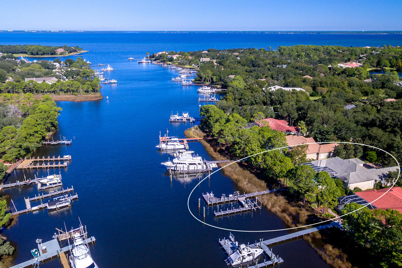 ATTENTION YACHTSMEN! FINEST DEEP-WATER IN DESTIN! Beautiful waterfront estate enjoying the coveted deep-water of scenic Indian Bayou and the exclusivity of Kelly Plantation, a magnificent gated golf and tennis community! The one-story floorplan offers a practical level of convenience and functionality, yet each room maintains a sense of privacy. Entertaining is a delight, as the screen-covered pool and hot tub, both a stone's throw from the Choctawhatchee Bay's indigenous edge, create sensational ambiance while extending the intimate living areas of the fabulous home to the extraordinary backyard.The dock configuration is exceptional, including slips large enough to accommodate a yacht, together with a smaller vessel and jet skis. The lot is gorgeous, further enhanced by...